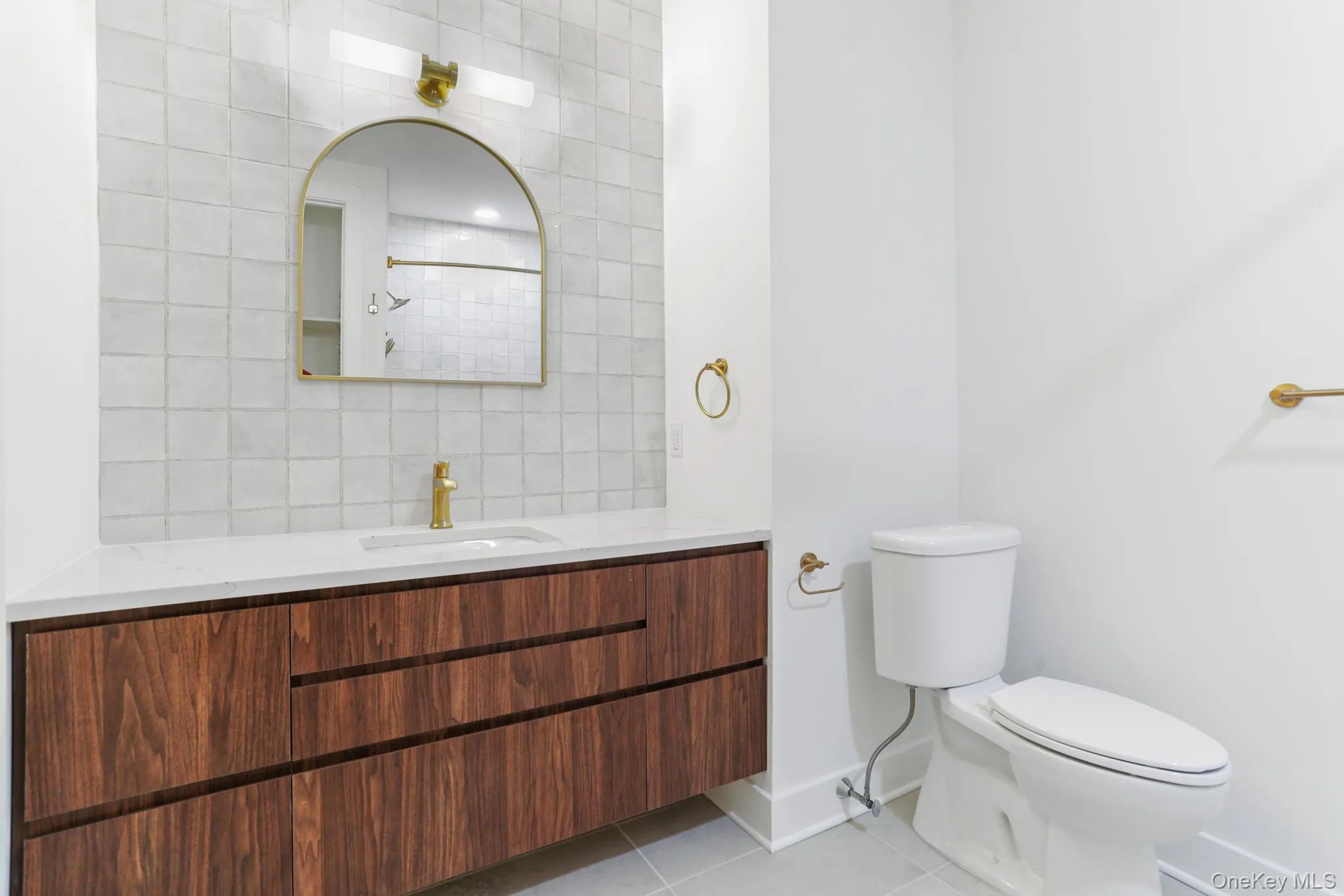 Bathroom featuring vanity, backsplash, light tile patterned floors, and a shower Bathroom featuring vanity, backsplash, light tile patterned floors, and a shower