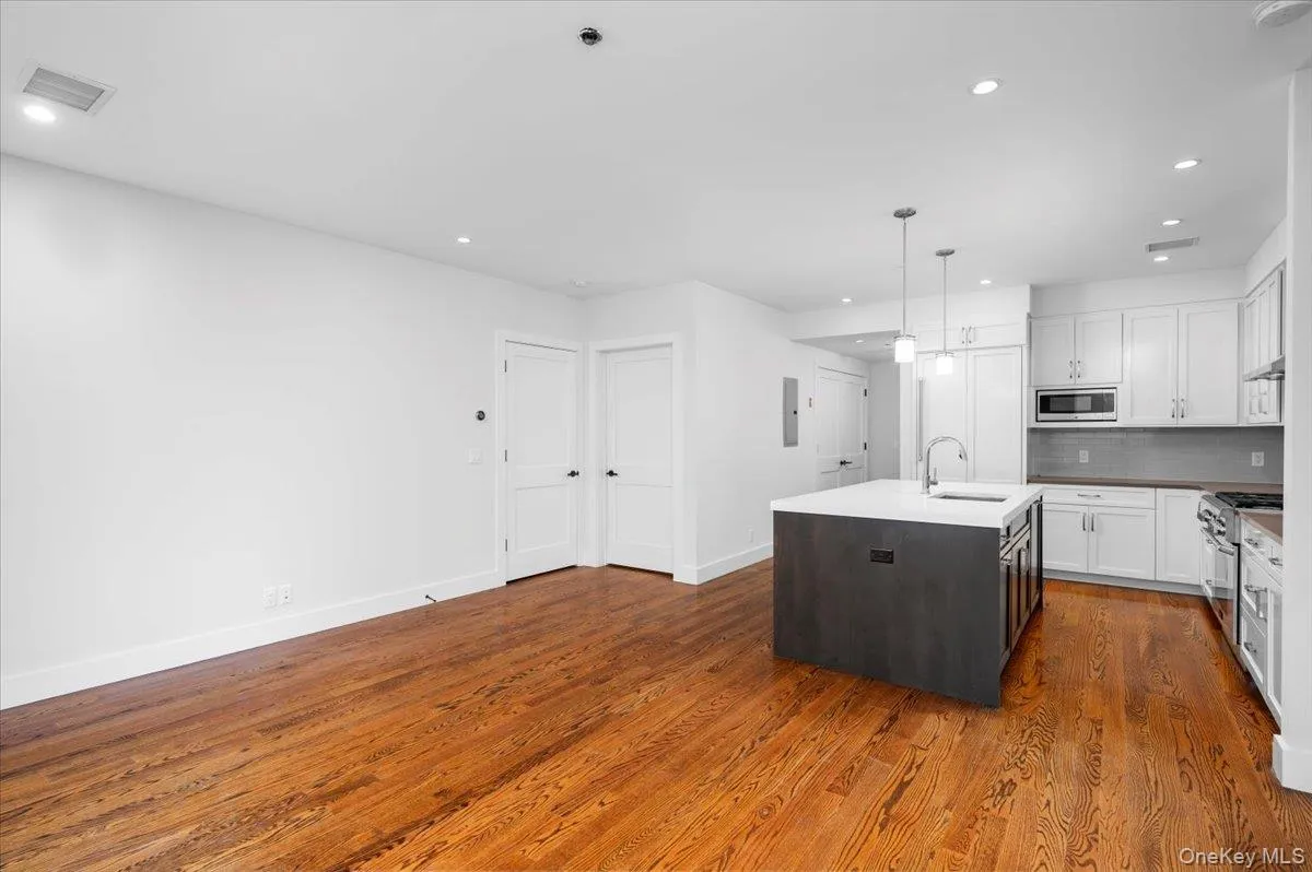 Kitchen with white cabinetry, a center island with sink, appliances with stainless steel finishes, dark brown cabinets, and dark wood finished floors Kitchen with white cabinetry, a center island with sink, appliances with stainless steel finishes, dark brown cabinets, and dark wood finished floors