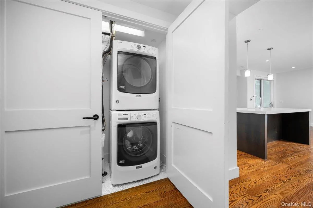 Washroom featuring estacked washer and dryer and light wood-style flooring Washroom featuring estacked washer and dryer and light wood-style flooring