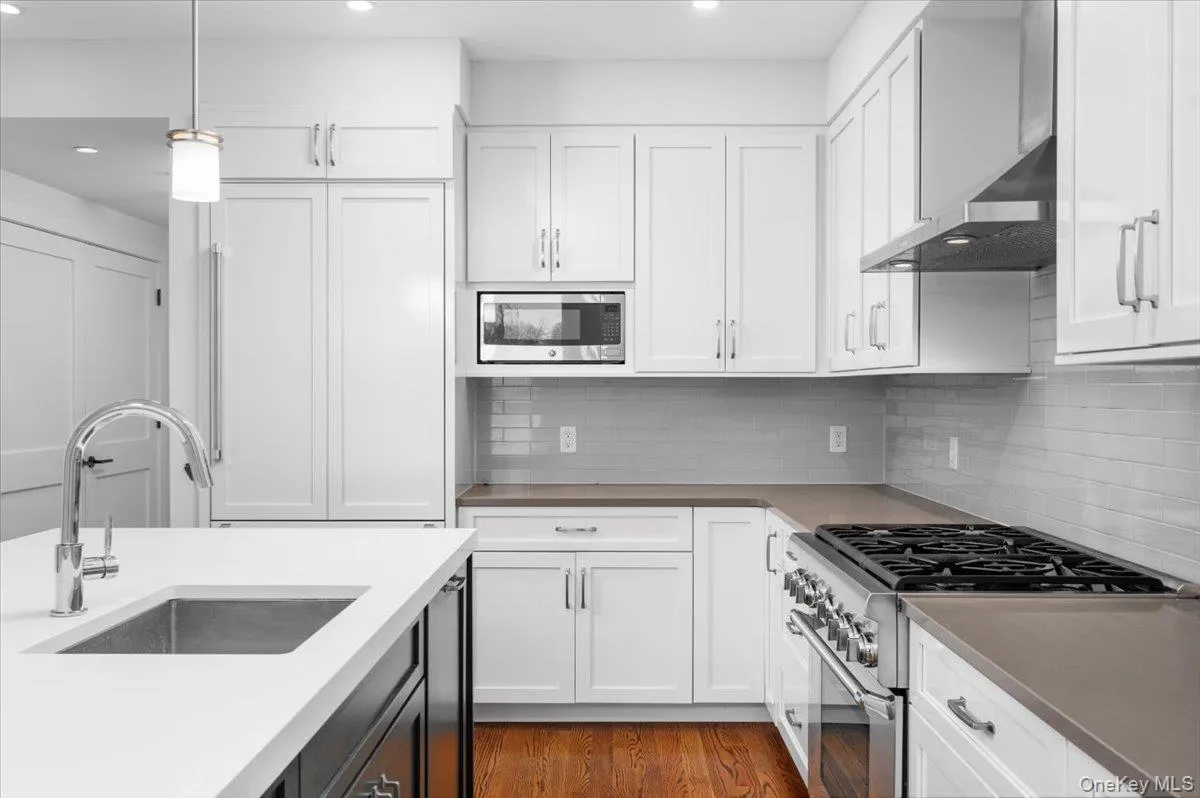 Kitchen featuring appliances with stainless steel finishes, white cabinetry, hanging light fixtures, and recessed lighting Kitchen featuring appliances with stainless steel finishes, white cabinetry, hanging light fixtures, and recessed lighting