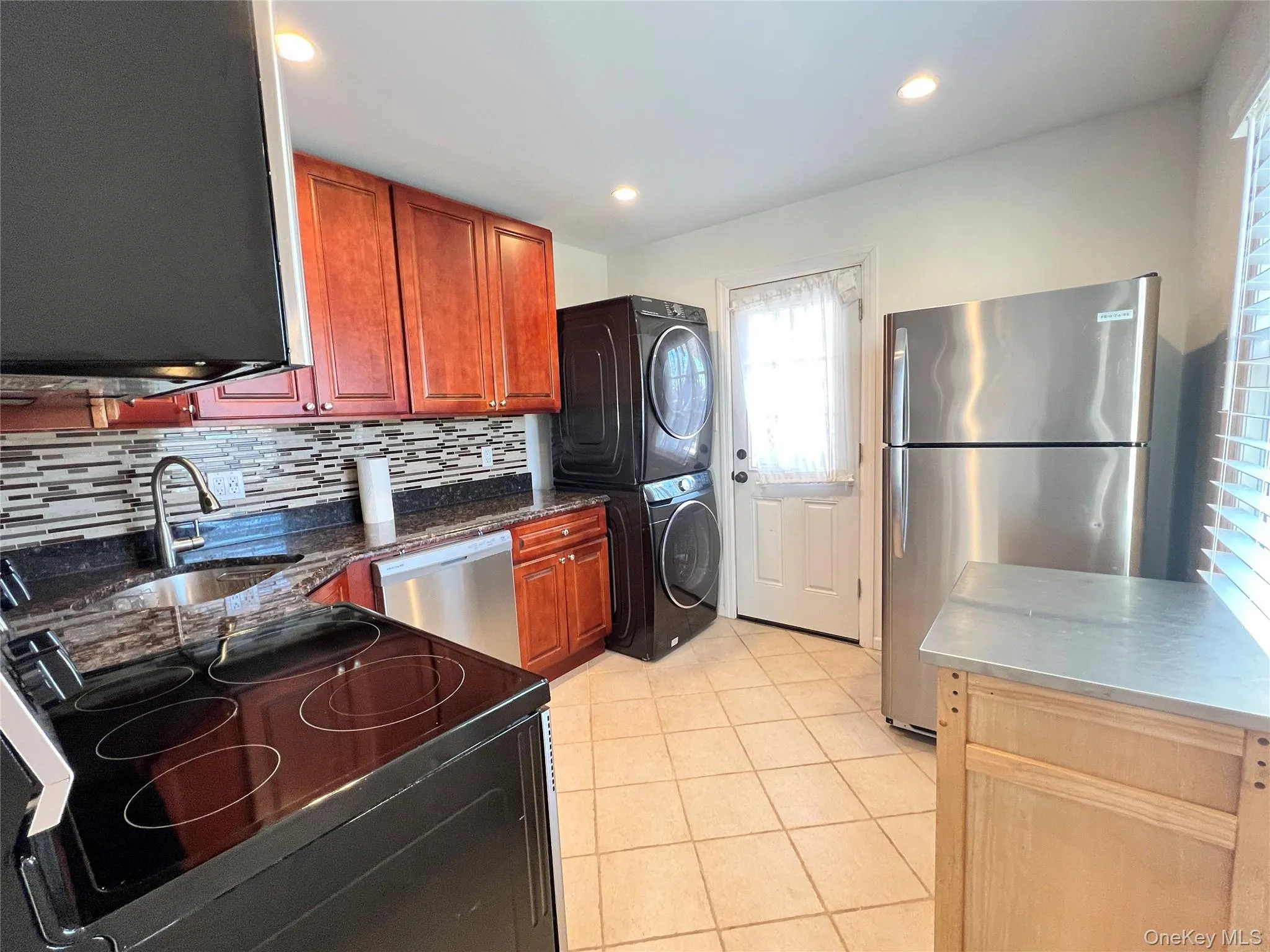 Kitchen featuring stainless steel appliances, tasteful backsplash, dark stone countertops, light tile patterned floors, and recessed lighting Kitchen featuring stainless steel appliances, tasteful backsplash, dark stone countertops, light tile patterned floors, and recessed lighting