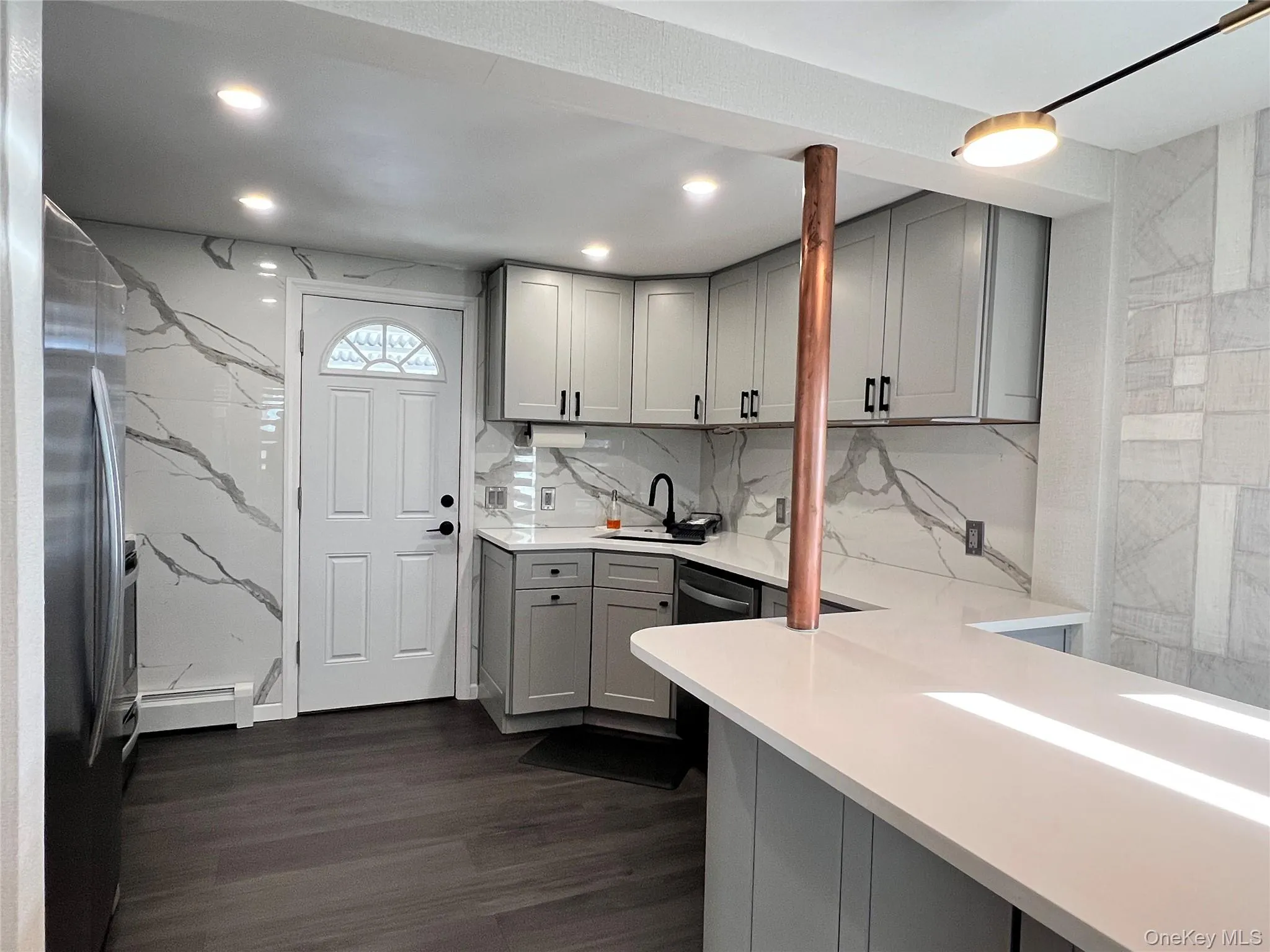 Kitchen with gray cabinetry, freestanding refrigerator, dark wood finished floors, and a baseboard heating unit Kitchen with gray cabinetry, freestanding refrigerator, dark wood finished floors, and a baseboard heating unit