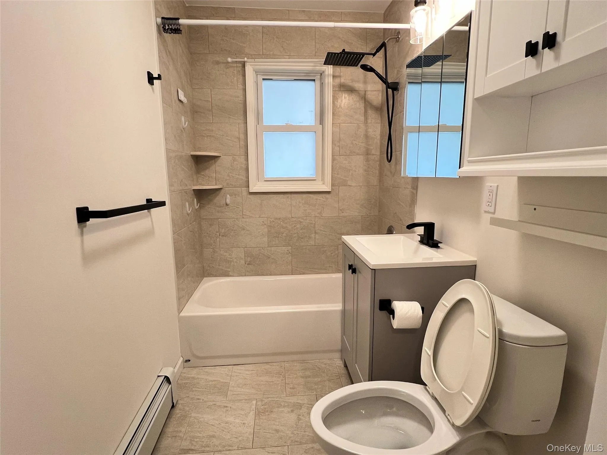 Full bathroom with a baseboard heating unit, vanity, and tub / shower combination Full bathroom with a baseboard heating unit, vanity, and tub / shower combination