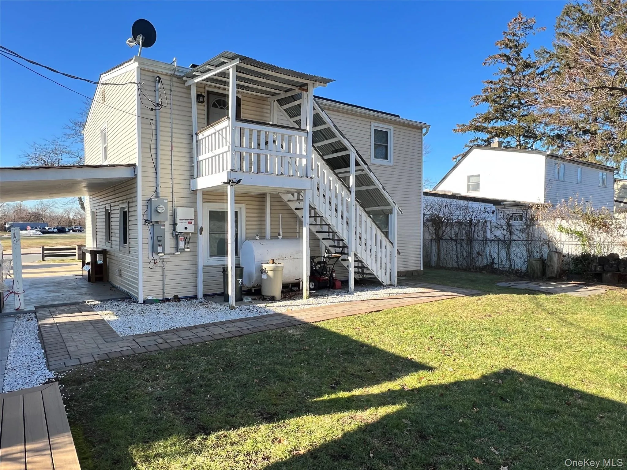 Back of house with stairs, oil tank, a wooden deck, and a patio Back of house with stairs, oil tank, a wooden deck, and a patio