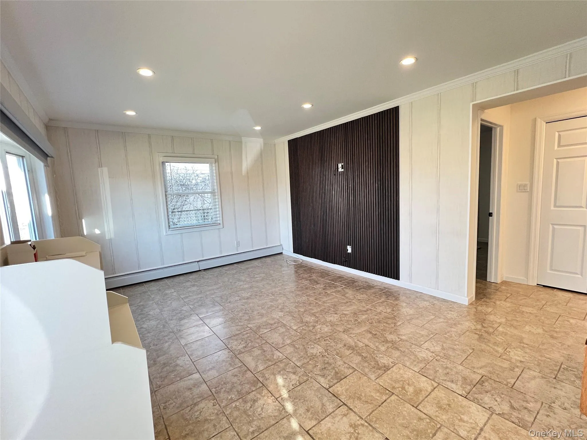 Unfurnished bedroom featuring ornamental molding, a baseboard radiator, recessed lighting, and multiple windows Unfurnished bedroom featuring ornamental molding, a baseboard radiator, recessed lighting, and multiple windows