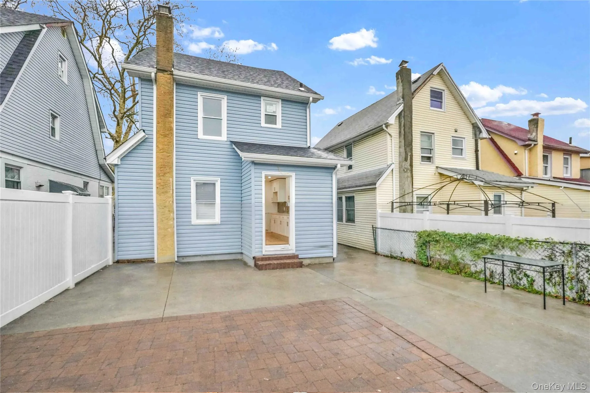 Rear view of property with a patio area, entry steps, a chimney, and roof with shingles Rear view of property with a patio area, entry steps, a chimney, and roof with shingles