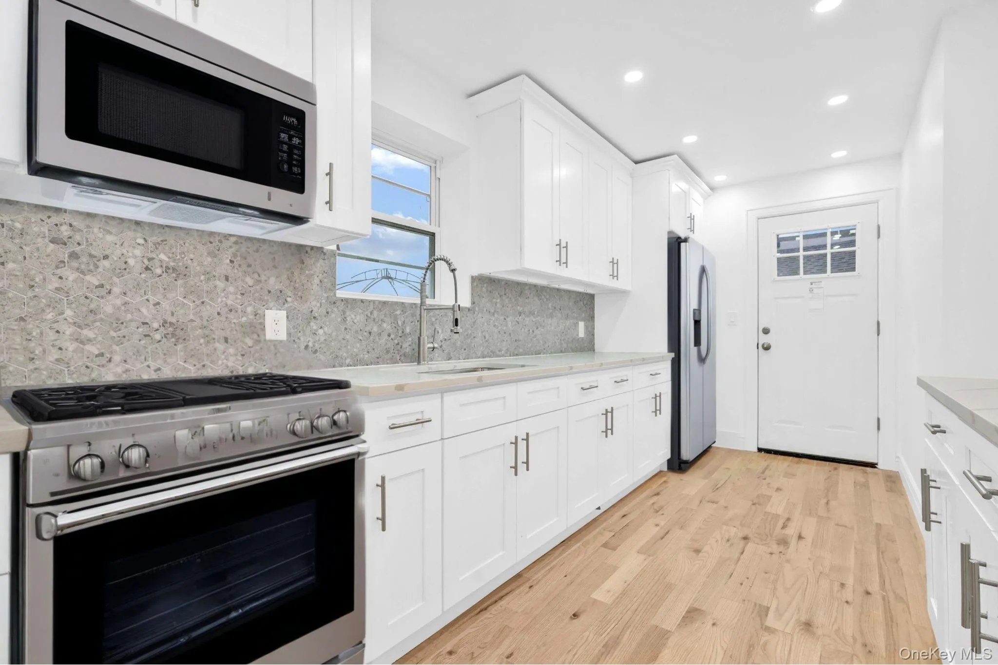 Kitchen featuring appliances with stainless steel finishes, white cabinets, light wood finished floors, and recessed lighting Kitchen featuring appliances with stainless steel finishes, white cabinets, light wood finished floors, and recessed lighting