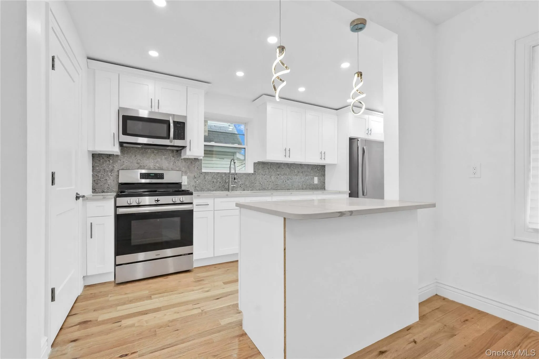 Kitchen featuring appliances with stainless steel finishes, recessed lighting, white cabinetry, hanging light fixtures, and tasteful backsplash Kitchen featuring appliances with stainless steel finishes, recessed lighting, white cabinetry, hanging light fixtures, and tasteful backsplash