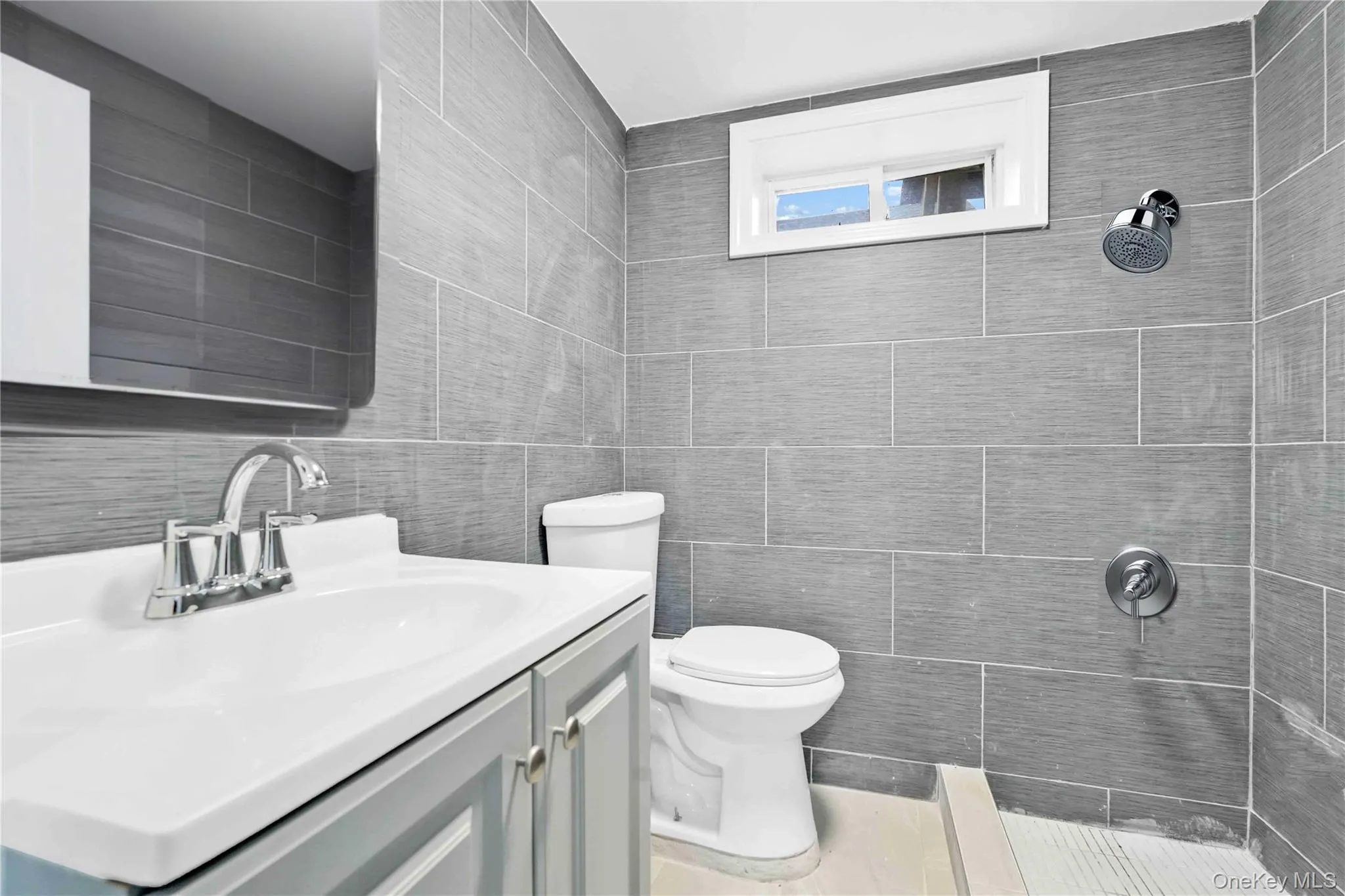 Bathroom with vanity, a tile shower, and tile walls Bathroom with vanity, a tile shower, and tile walls