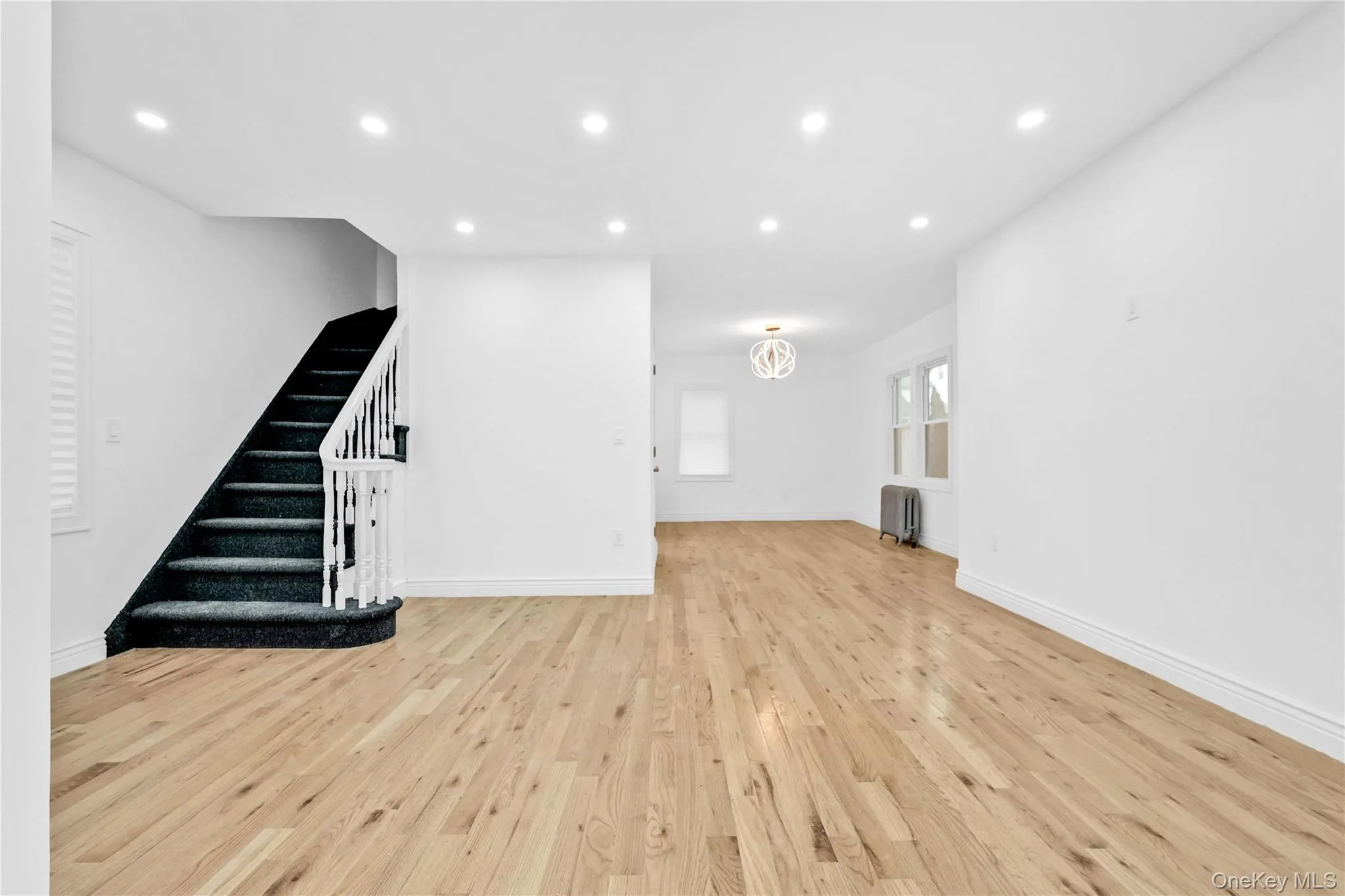Unfurnished living room with recessed lighting, light wood-style flooring, stairway, and radiator heating unit Unfurnished living room with recessed lighting, light wood-style flooring, stairway, and radiator heating unit