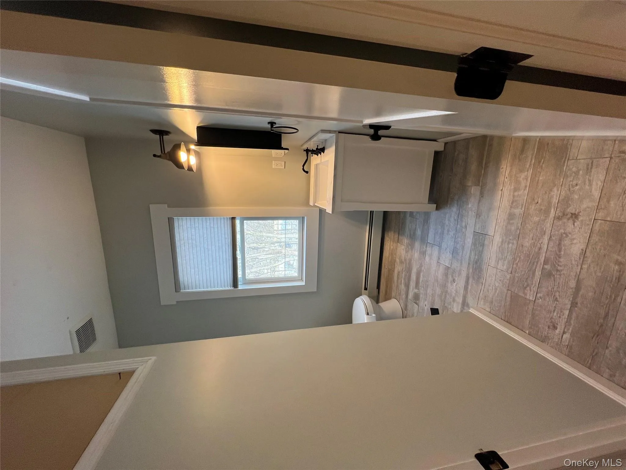 Bathroom featuring toilet, a baseboard heating unit, vanity, wood finished floors, and baseboards Bathroom featuring toilet, a baseboard heating unit, vanity, wood finished floors, and baseboards