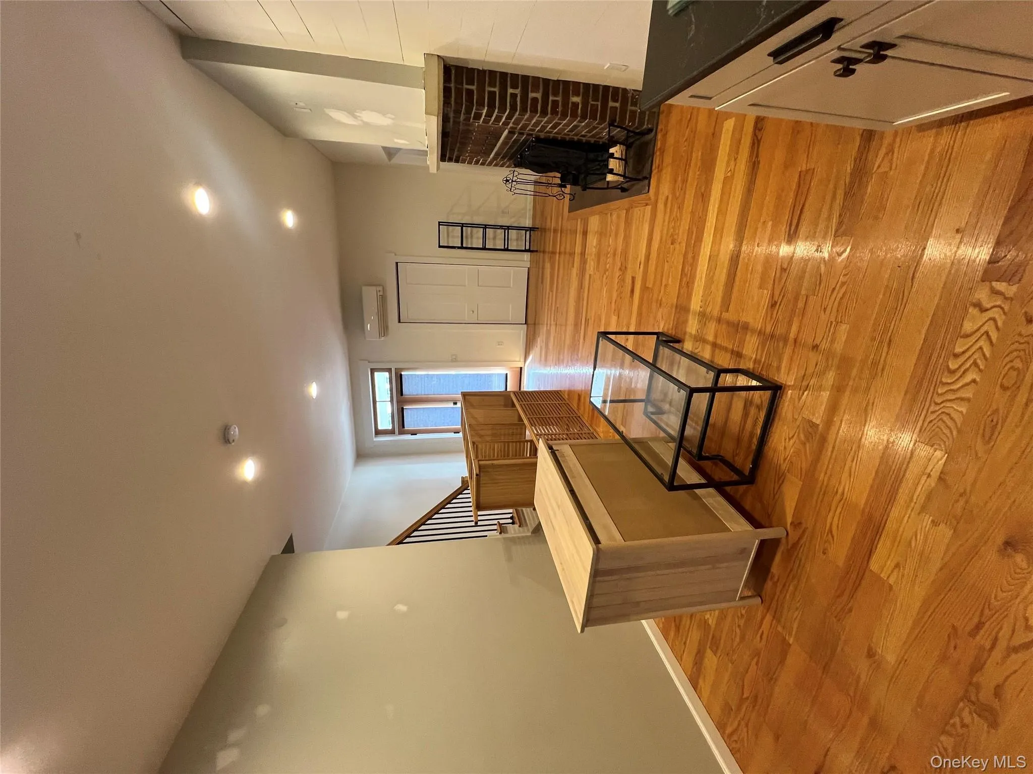 Living room featuring a wall unit AC, recessed lighting, stairway, light wood-style floors, and a brick fireplace Living room featuring a wall unit AC, recessed lighting, stairway, light wood-style floors, and a brick fireplace