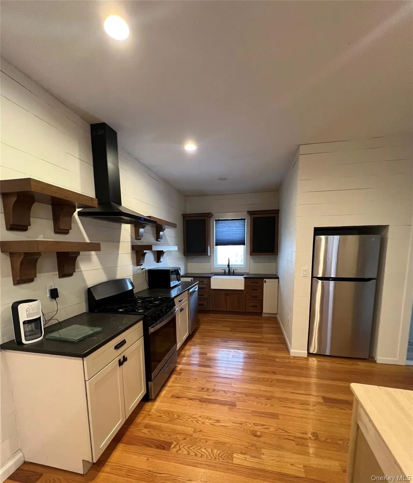 Kitchen with light wood finished floors, stainless steel appliances, white cabinetry, a sink, and extractor fan Kitchen with light wood finished floors, stainless steel appliances, white cabinetry, a sink, and extractor fan