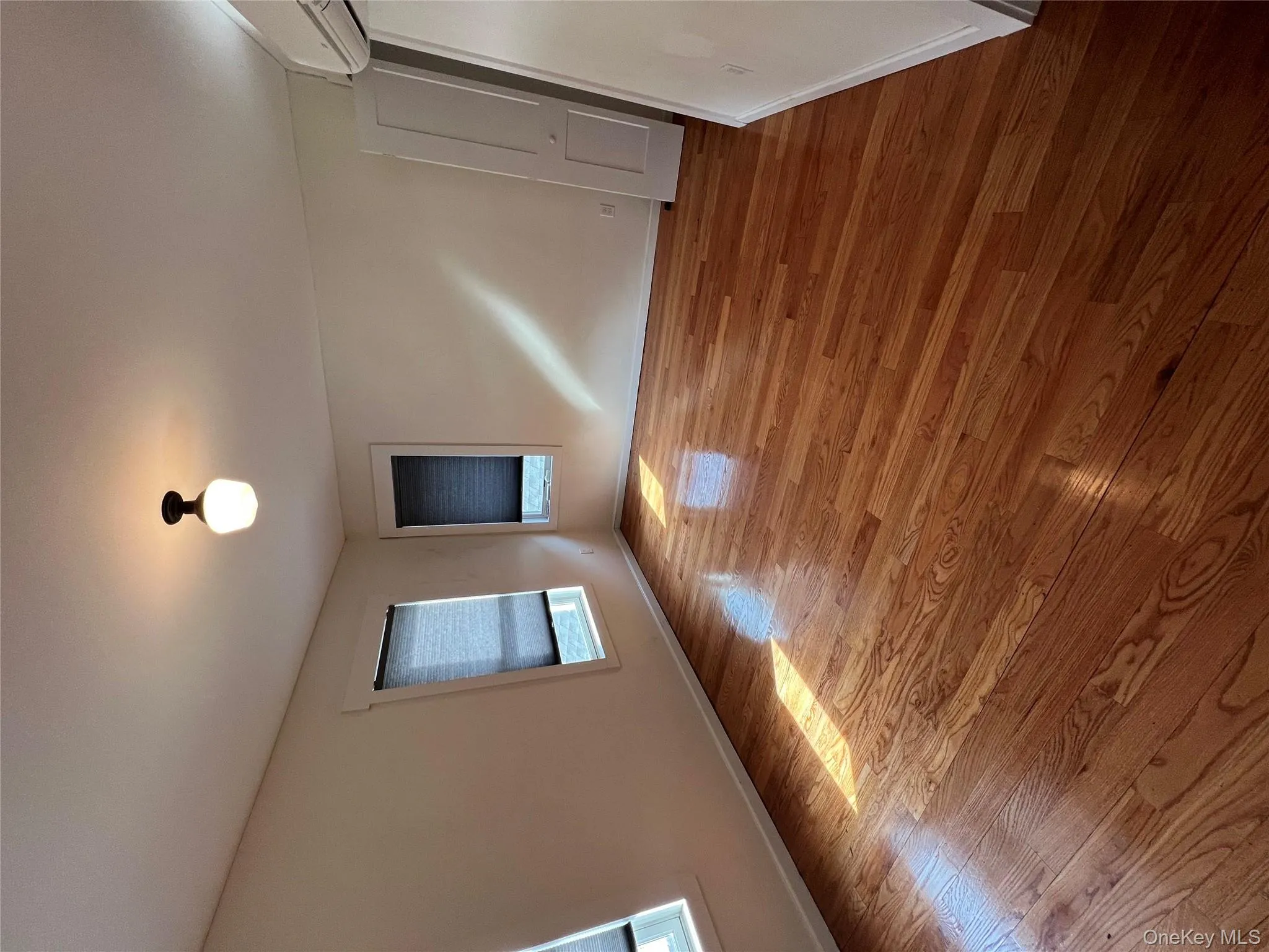 Spare room featuring baseboards, wood finished floors, and an AC wall unit Spare room featuring baseboards, wood finished floors, and an AC wall unit
