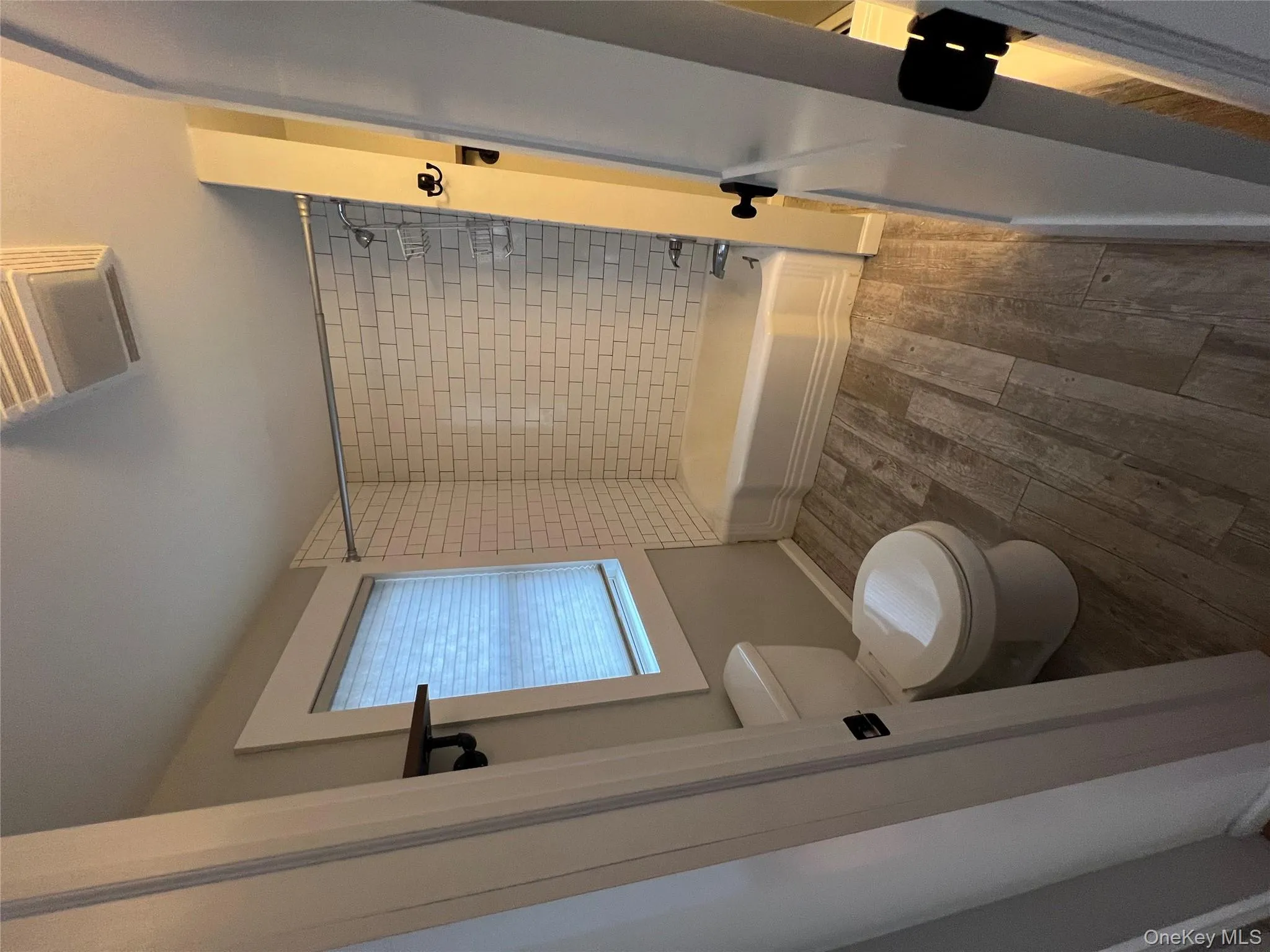 Bathroom featuring baseboards, bathing tub / shower combination, toilet, and wood finished floors Bathroom featuring baseboards, bathing tub / shower combination, toilet, and wood finished floors