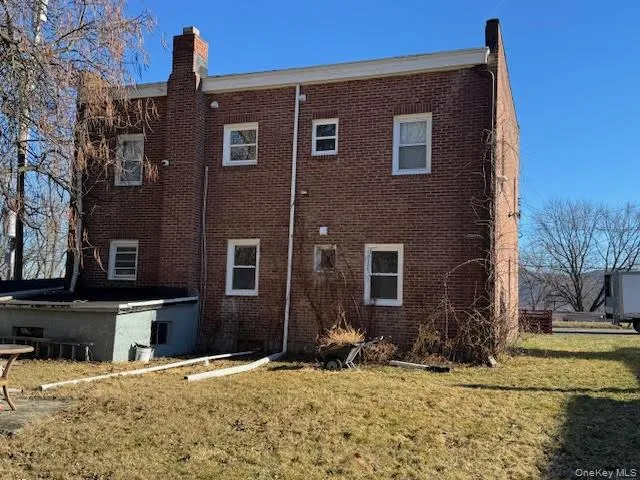 Rear view of property featuring a chimney, brick siding, and a lawn Rear view of property featuring a chimney, brick siding, and a lawn