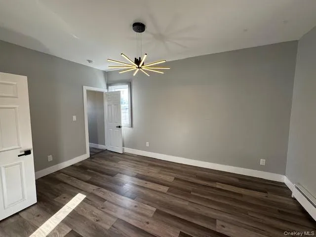 Unfurnished bedroom featuring new flooring, a baseboard radiator, an ceiling light. Unfurnished bedroom featuring new flooring, a baseboard radiator, an ceiling light.