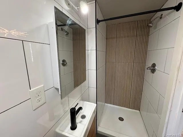 Full bathroom featuring vanity and a shower stall with ceramic tile walls. Full bathroom featuring vanity and a shower stall with ceramic tile walls.