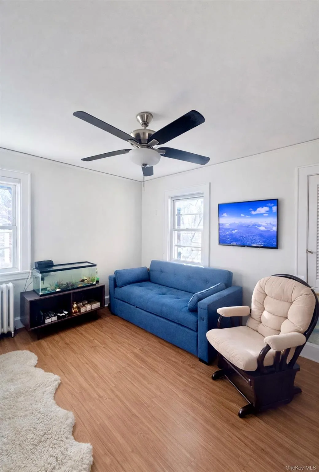 Living room featuring wood finished floors, radiator heating unit, and a ceiling fan Living room featuring wood finished floors, radiator heating unit, and a ceiling fan