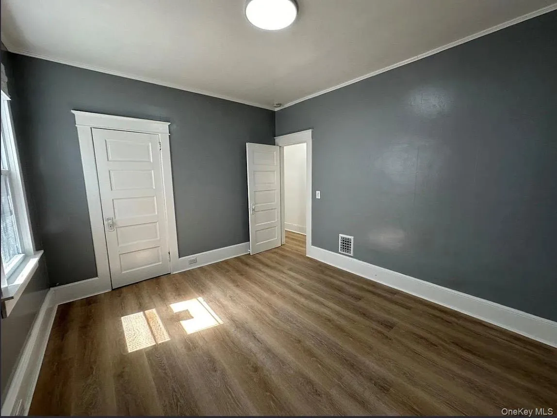 Unfurnished bedroom featuring crown molding, wood finished floors, and a closet Unfurnished bedroom featuring crown molding, wood finished floors, and a closet