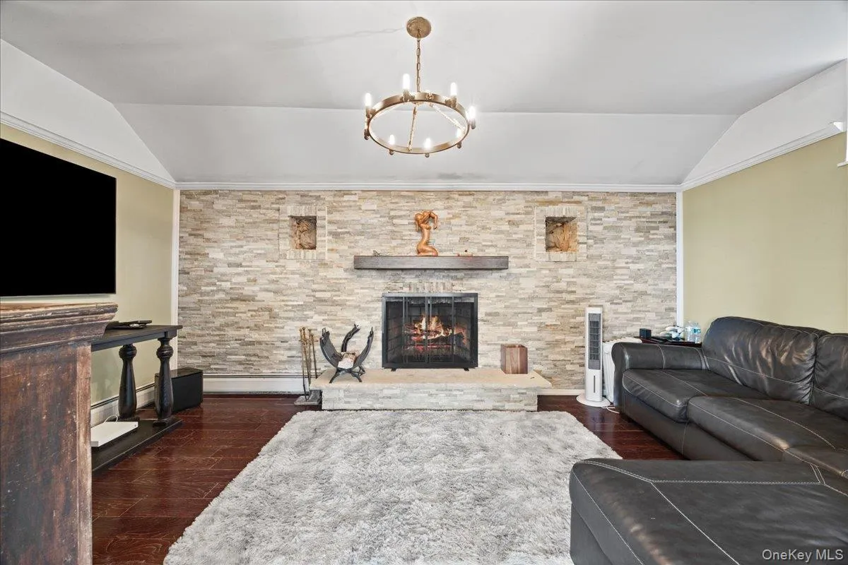 Living area featuring a stone fireplace and chandelier Living area featuring a stone fireplace and chandelier