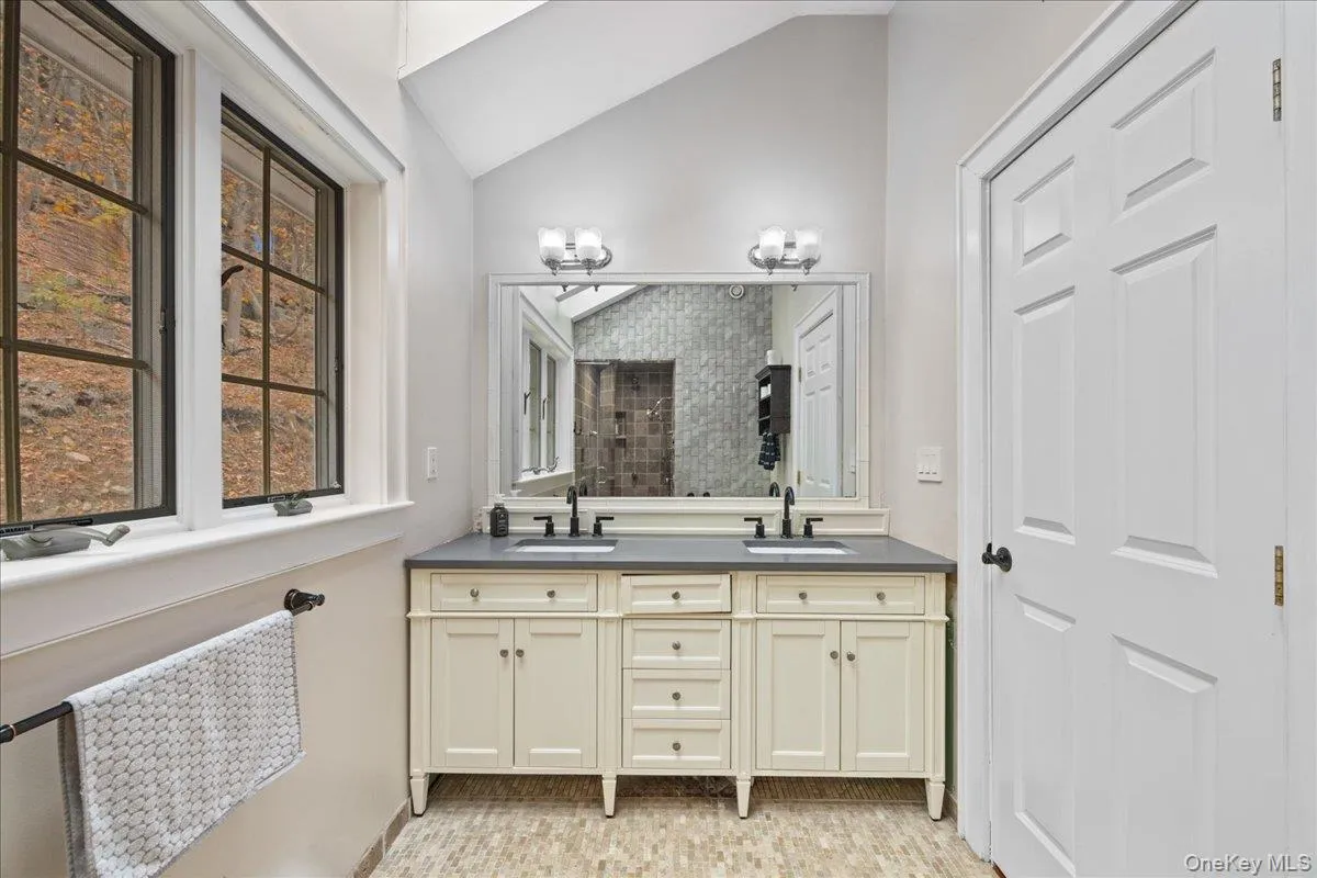 Full bath featuring lofted ceiling, double vanity, and tiled shower Full bath featuring lofted ceiling, double vanity, and tiled shower
