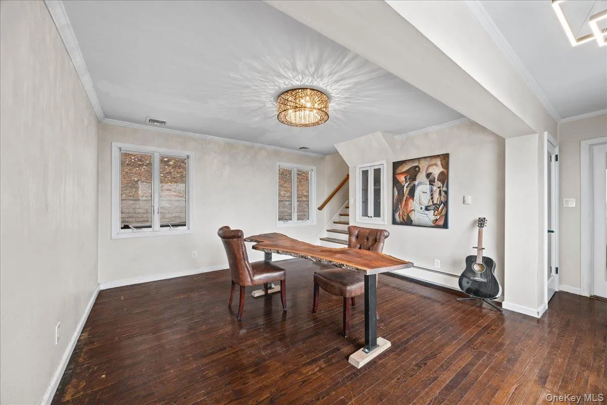 Dining space featuring dark wood-style floors, crown molding, stairs, and a chandelier Dining space featuring dark wood-style floors, crown molding, stairs, and a chandelier