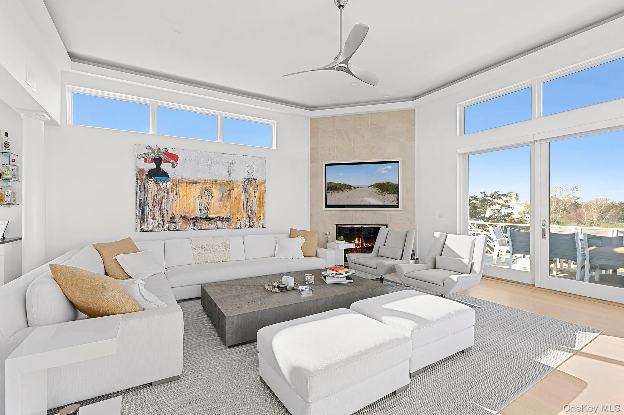 Living room with ceiling fan, a tiled fireplace, wood finished floors, and a towering ceiling Living room with ceiling fan, a tiled fireplace, wood finished floors, and a towering ceiling