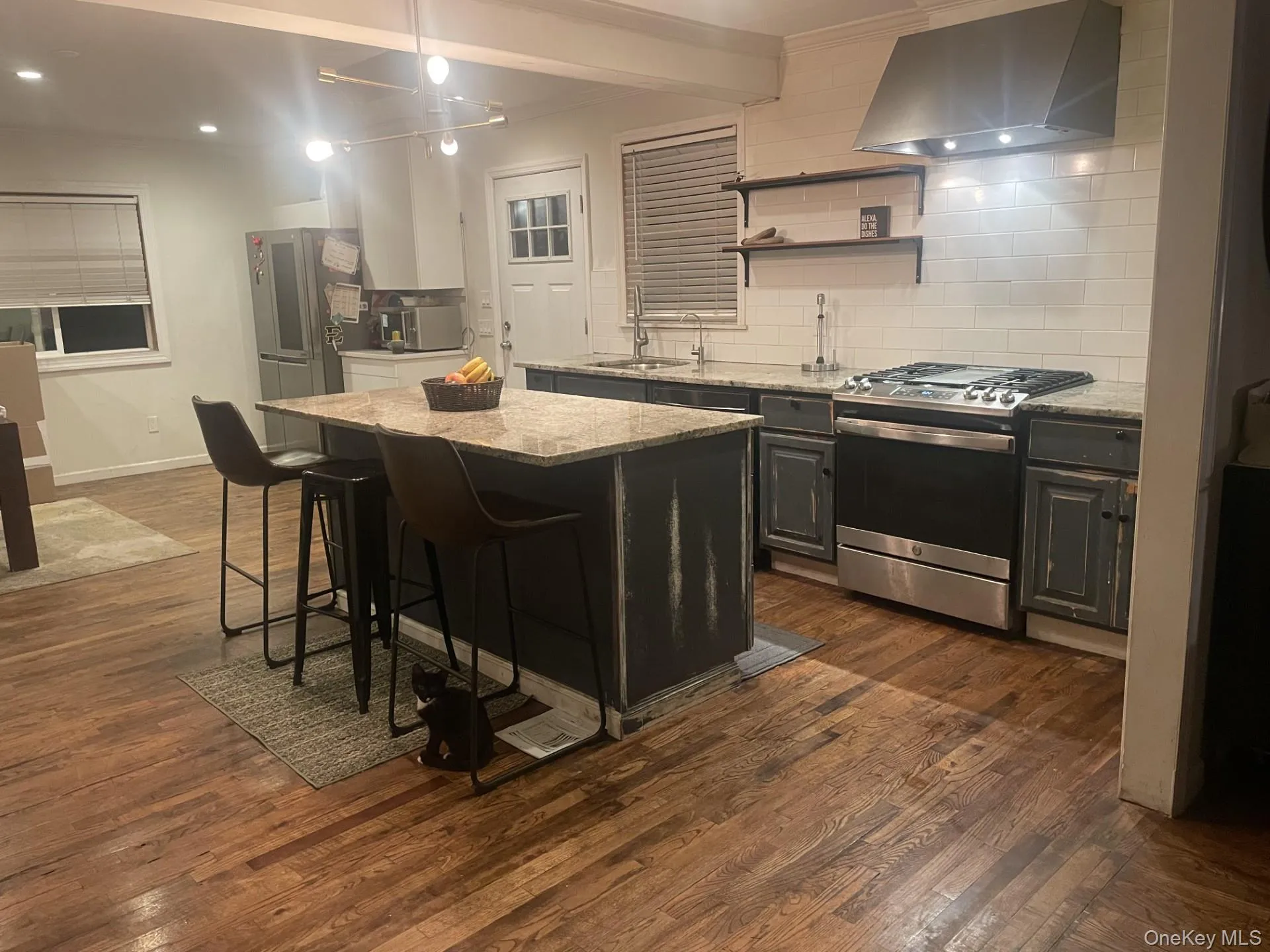 Kitchen featuring backsplash, range hood, stainless steel appliances, a kitchen bar, and a kitchen island Kitchen featuring backsplash, range hood, stainless steel appliances, a kitchen bar, and a kitchen island