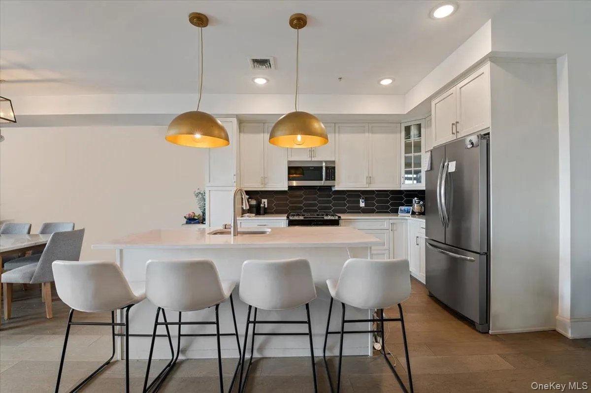 Kitchen with stainless steel appliances, a breakfast bar area, white cabinets, decorative backsplash, and recessed lighting Kitchen with stainless steel appliances, a breakfast bar area, white cabinets, decorative backsplash, and recessed lighting