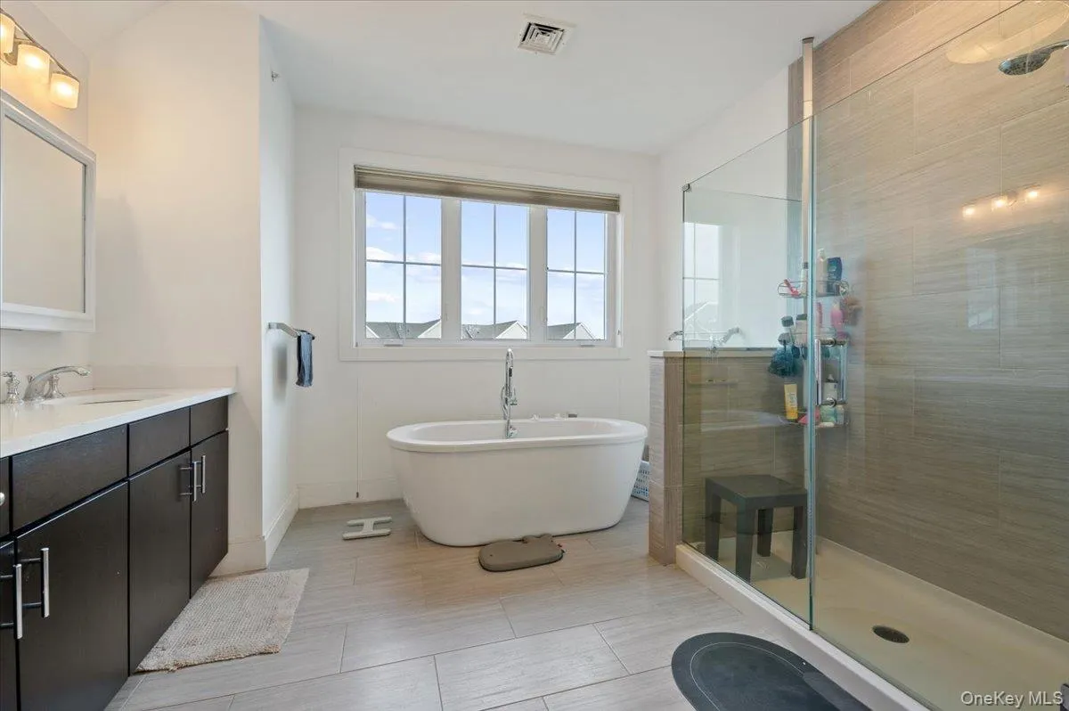 Bathroom featuring vanity, a soaking tub, a shower stall, and light tile patterned floors Bathroom featuring vanity, a soaking tub, a shower stall, and light tile patterned floors