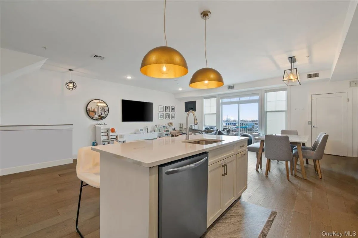 Kitchen with open floor plan, stainless steel dishwasher, light wood-type flooring, and a center island with sink Kitchen with open floor plan, stainless steel dishwasher, light wood-type flooring, and a center island with sink