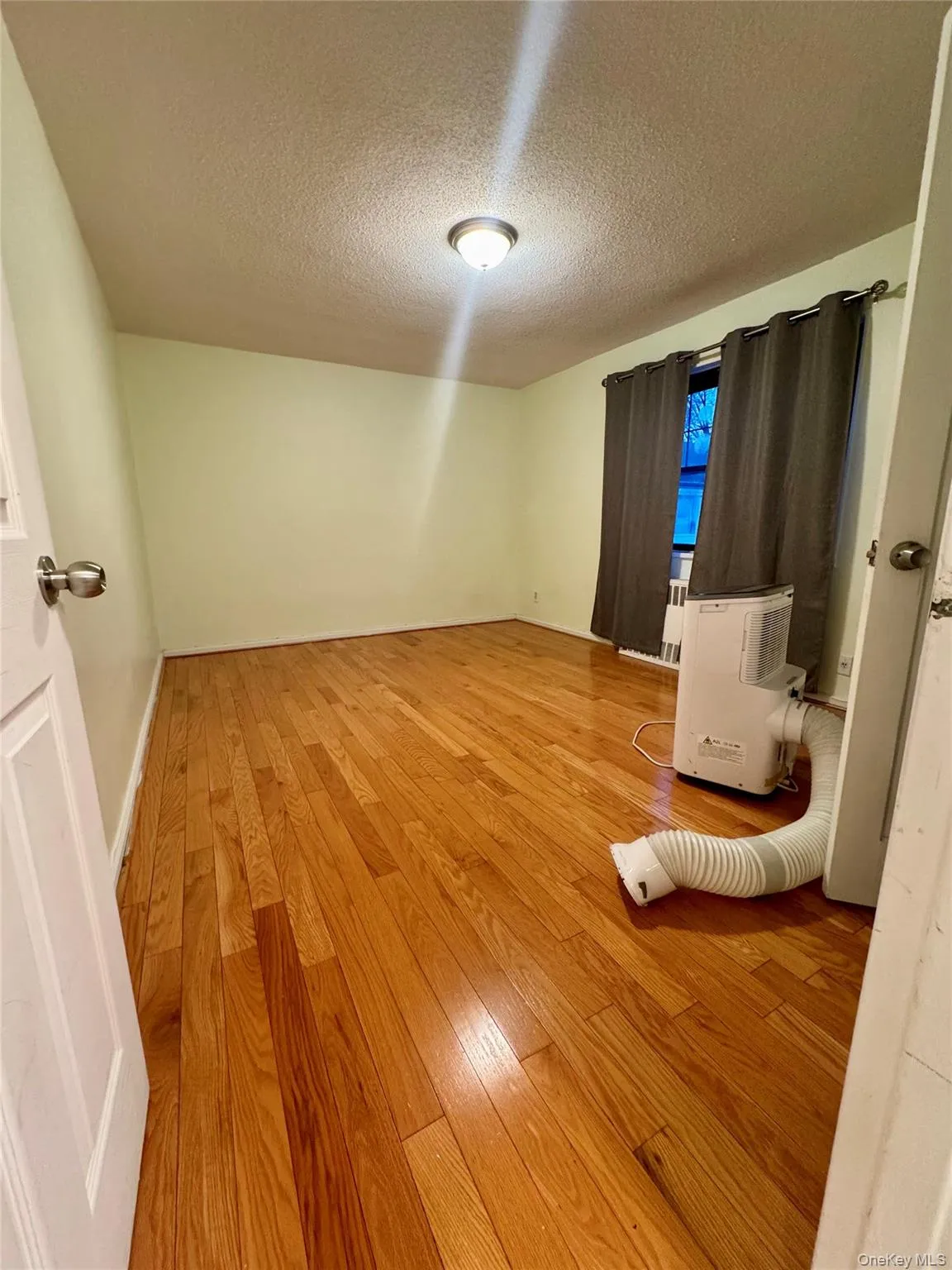 Empty room featuring light wood-style flooring and a textured ceiling Empty room featuring light wood-style flooring and a textured ceiling