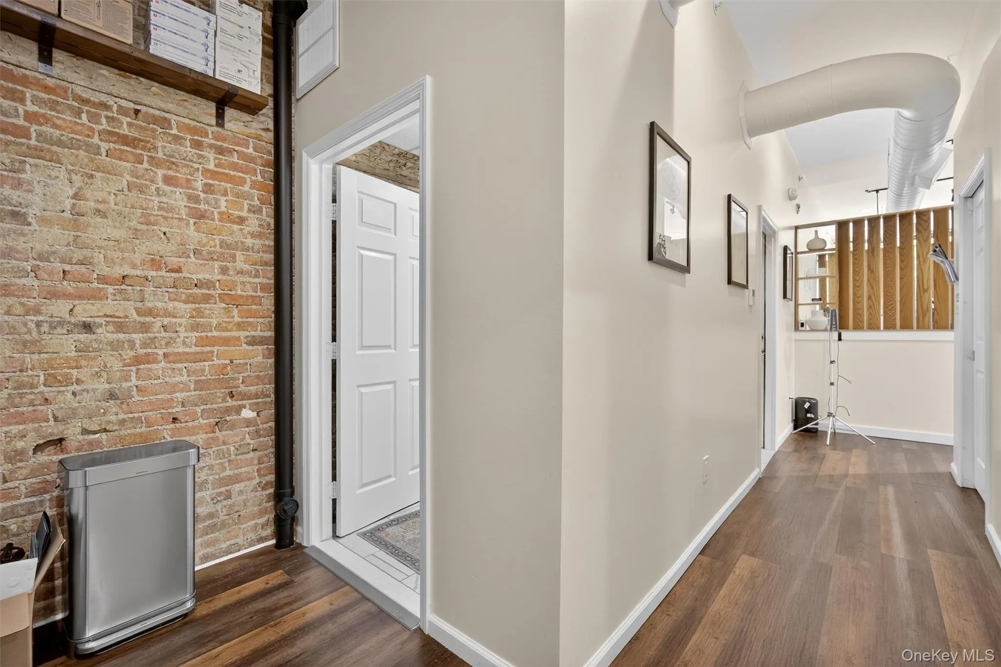 Corridor featuring dark wood-style flooring and brick wall Corridor featuring dark wood-style flooring and brick wall