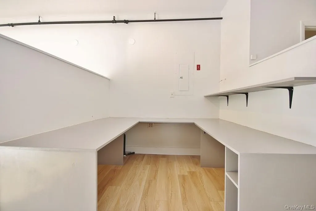 Unfurnished office featuring light wood-style floors and electric panel Unfurnished office featuring light wood-style floors and electric panel