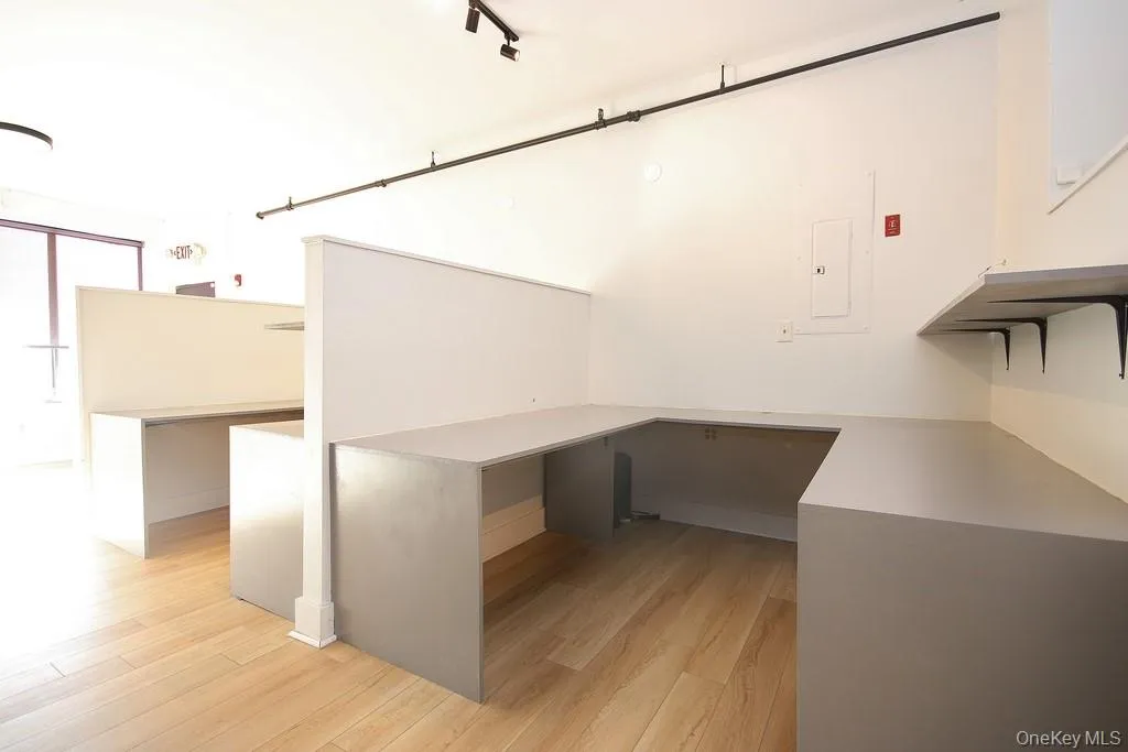 Unfurnished office featuring light wood finished floors and electric panel Unfurnished office featuring light wood finished floors and electric panel