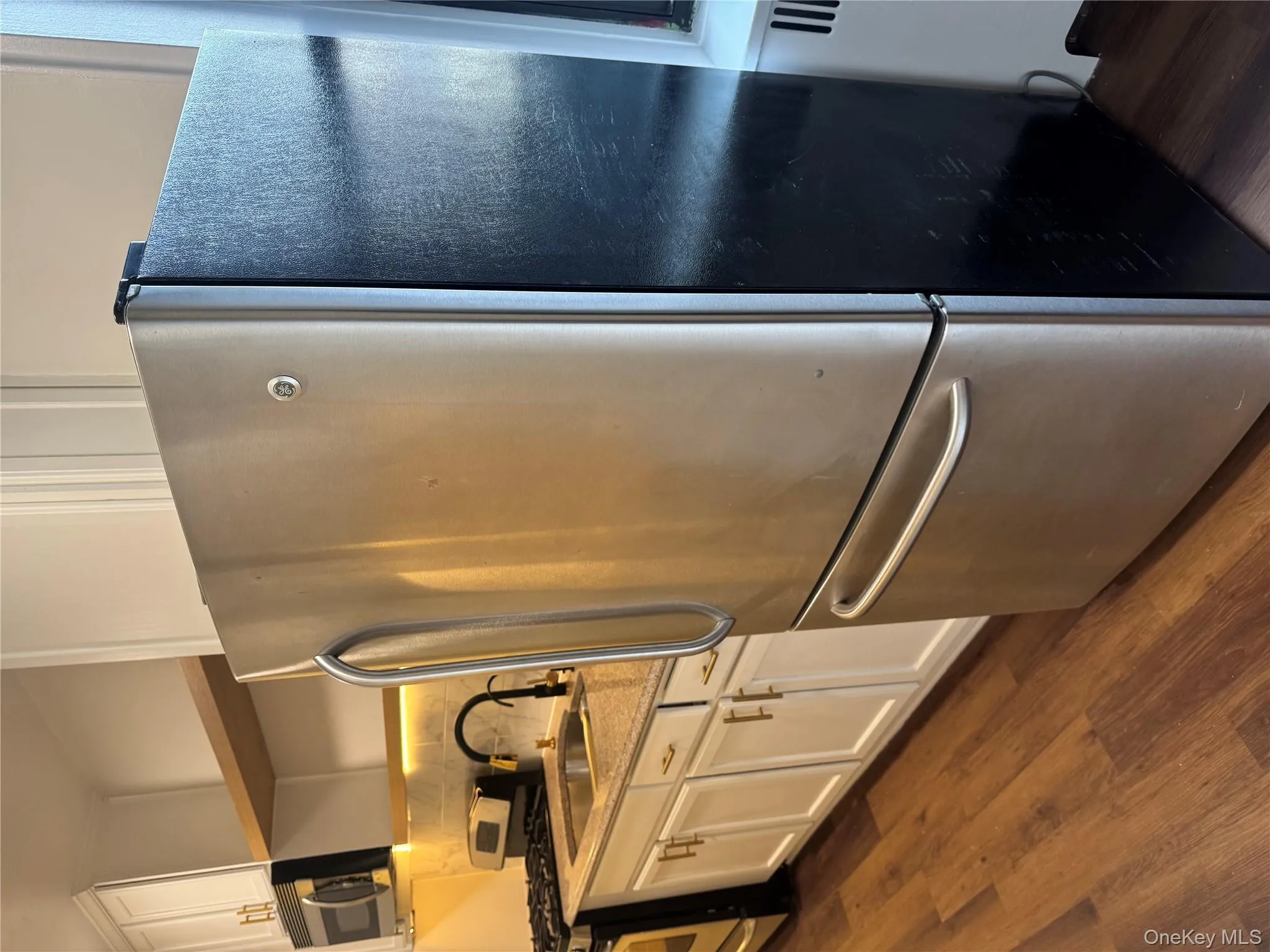 Kitchen with appliances with stainless steel finishes, white cabinets, open shelves, and dark wood-type flooring Kitchen with appliances with stainless steel finishes, white cabinets, open shelves, and dark wood-type flooring