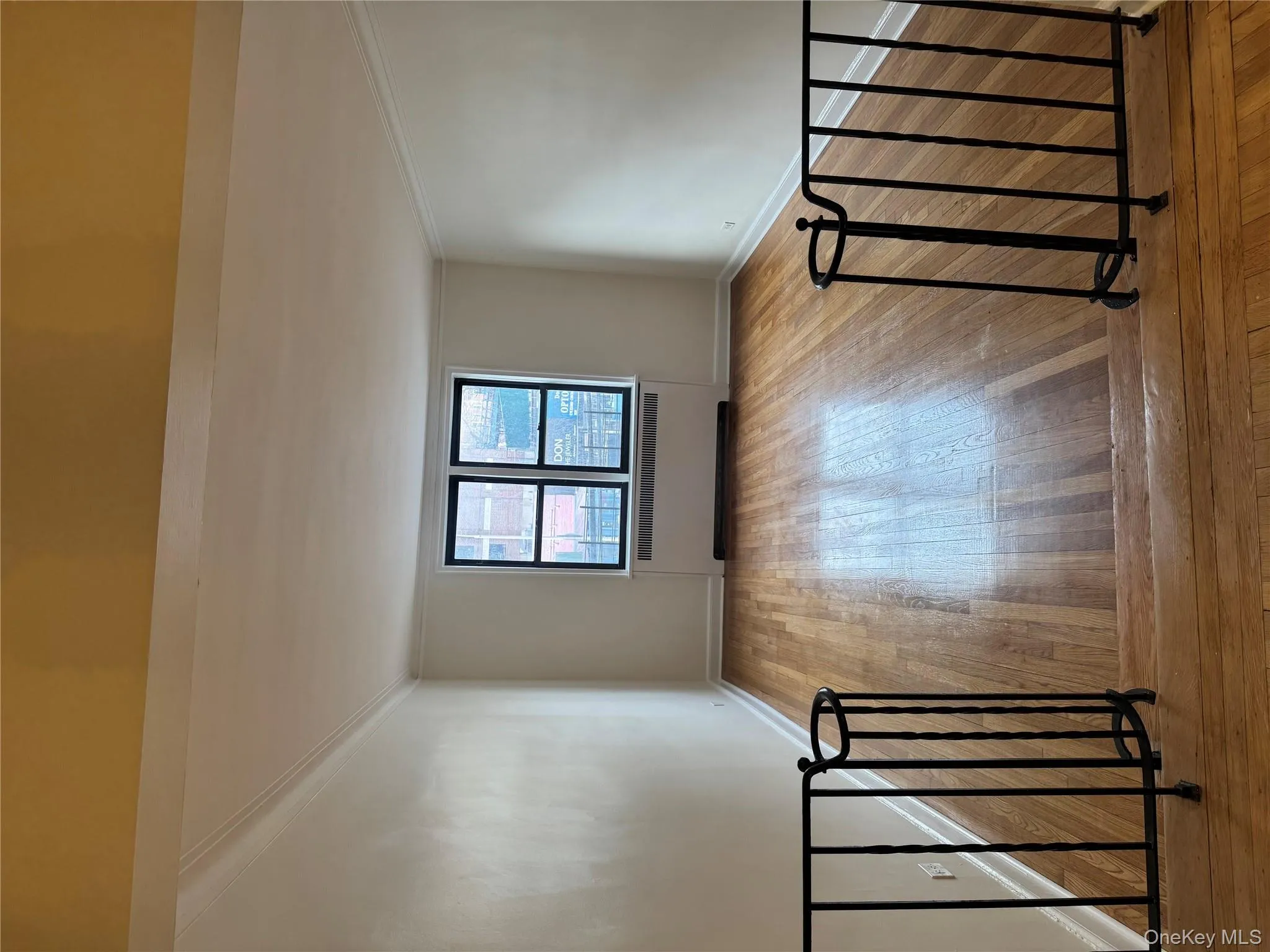 Empty room featuring radiator heating unit, light wood-style flooring, and crown molding Empty room featuring radiator heating unit, light wood-style flooring, and crown molding
