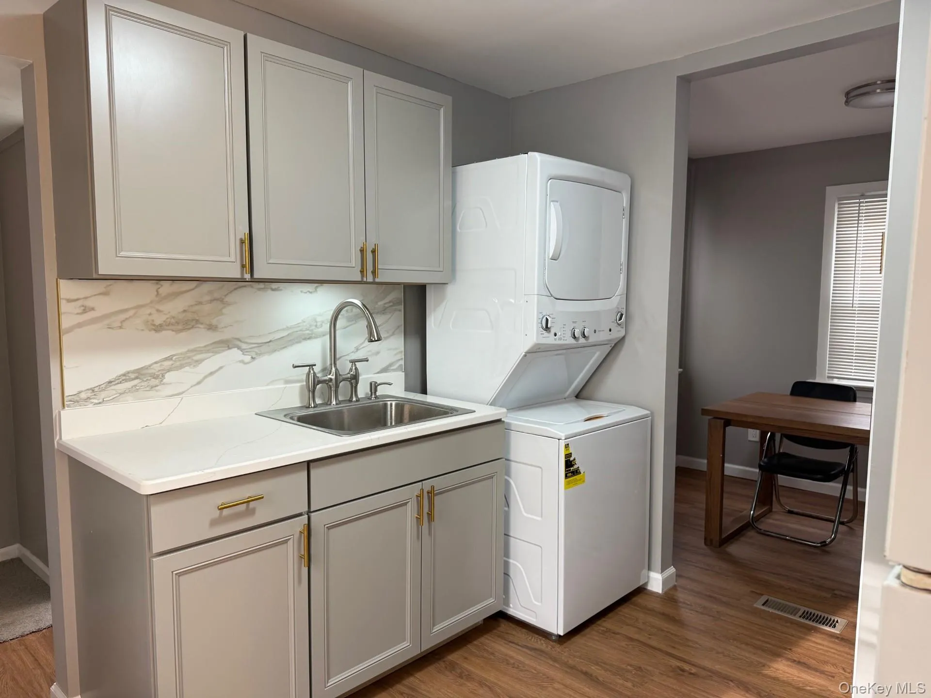 Washroom with stacked washer / dryer and dark wood-type flooring Washroom with stacked washer / dryer and dark wood-type flooring