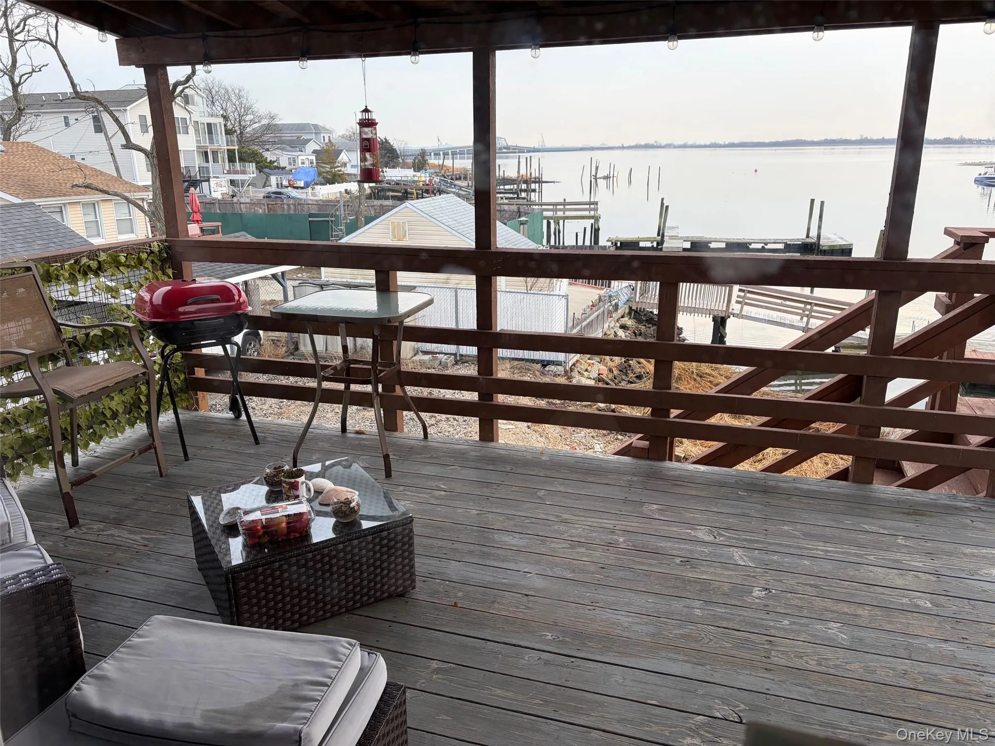 Wooden terrace with a water view, a grill, boat lift, and a boat dock Wooden terrace with a water view, a grill, boat lift, and a boat dock