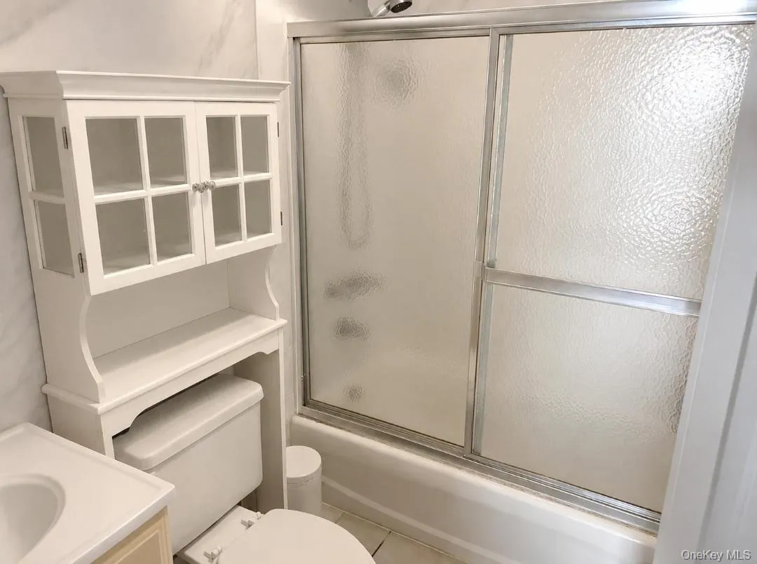 Bathroom featuring enclosed tub / shower combo, light tile patterned floors, and vanity Bathroom featuring enclosed tub / shower combo, light tile patterned floors, and vanity