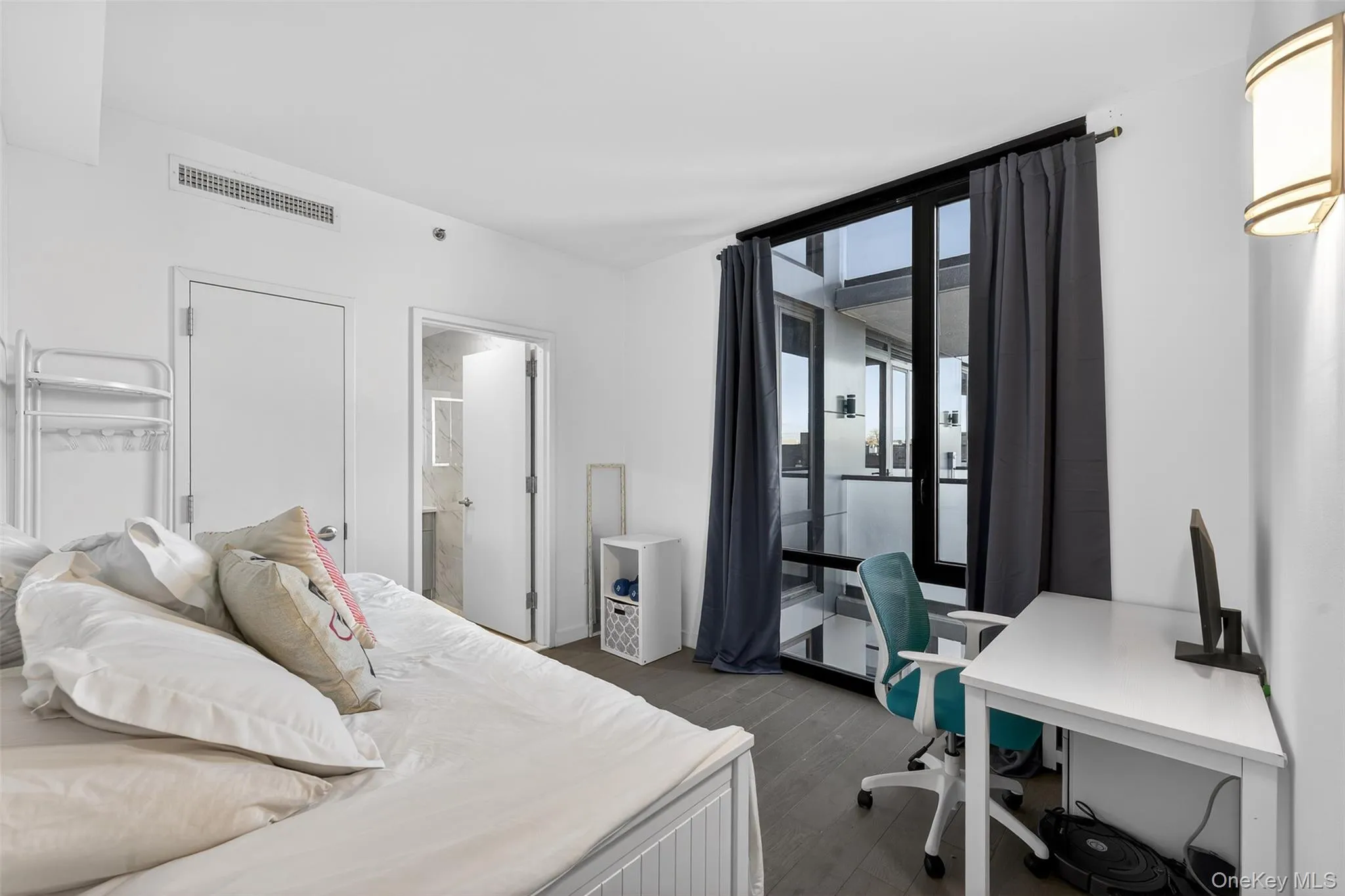 Bedroom with dark wood-style floors, a desk, ensuite bath, and a wall of windows Bedroom with dark wood-style floors, a desk, ensuite bath, and a wall of windows