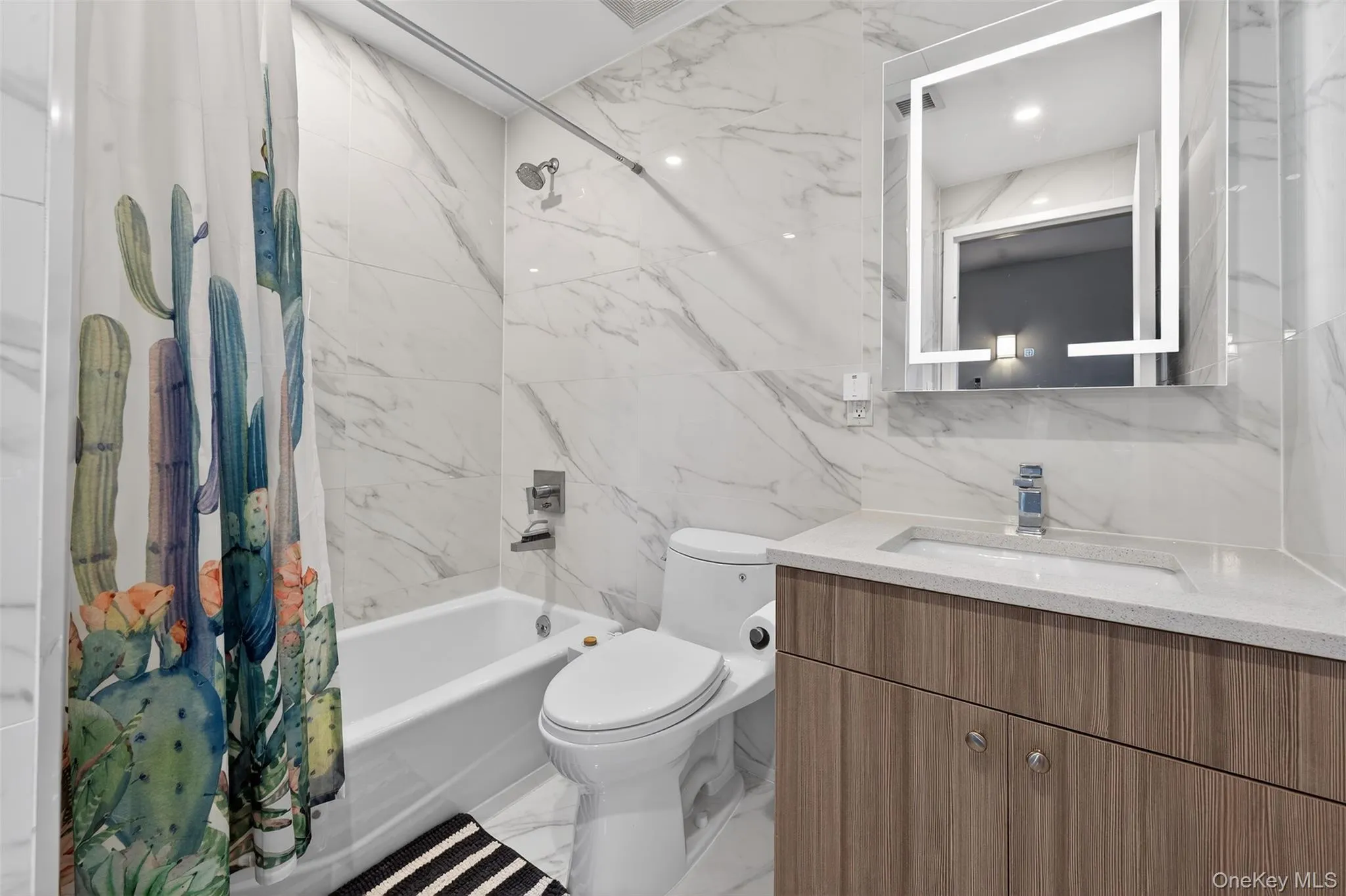 Bathroom with tile walls, shower / tub combo with curtain, light marble finish flooring, and vanity Bathroom with tile walls, shower / tub combo with curtain, light marble finish flooring, and vanity