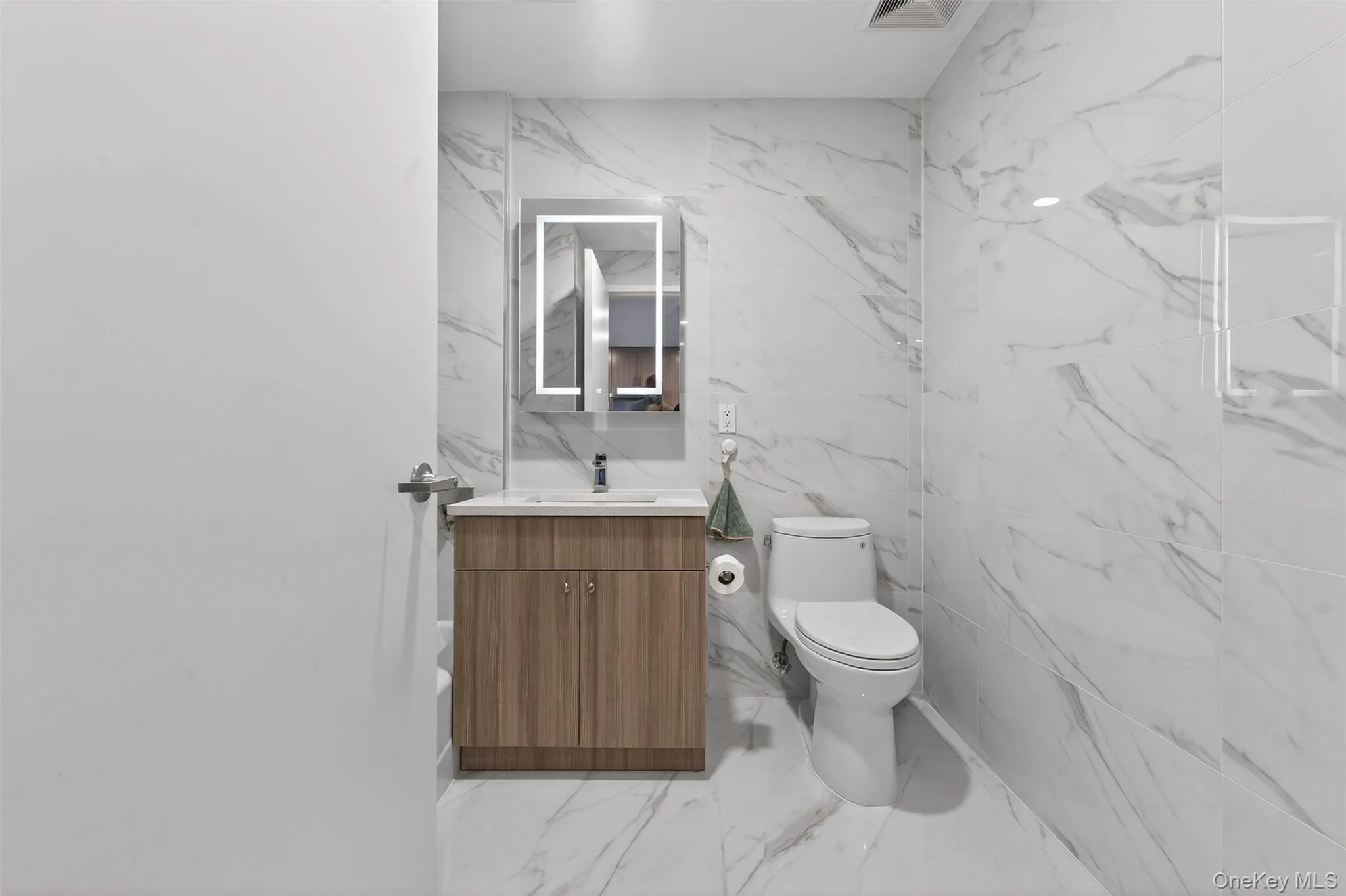 Full bathroom featuring vanity, tile walls, stone wall, and light marble finish flooring Full bathroom featuring vanity, tile walls, stone wall, and light marble finish flooring