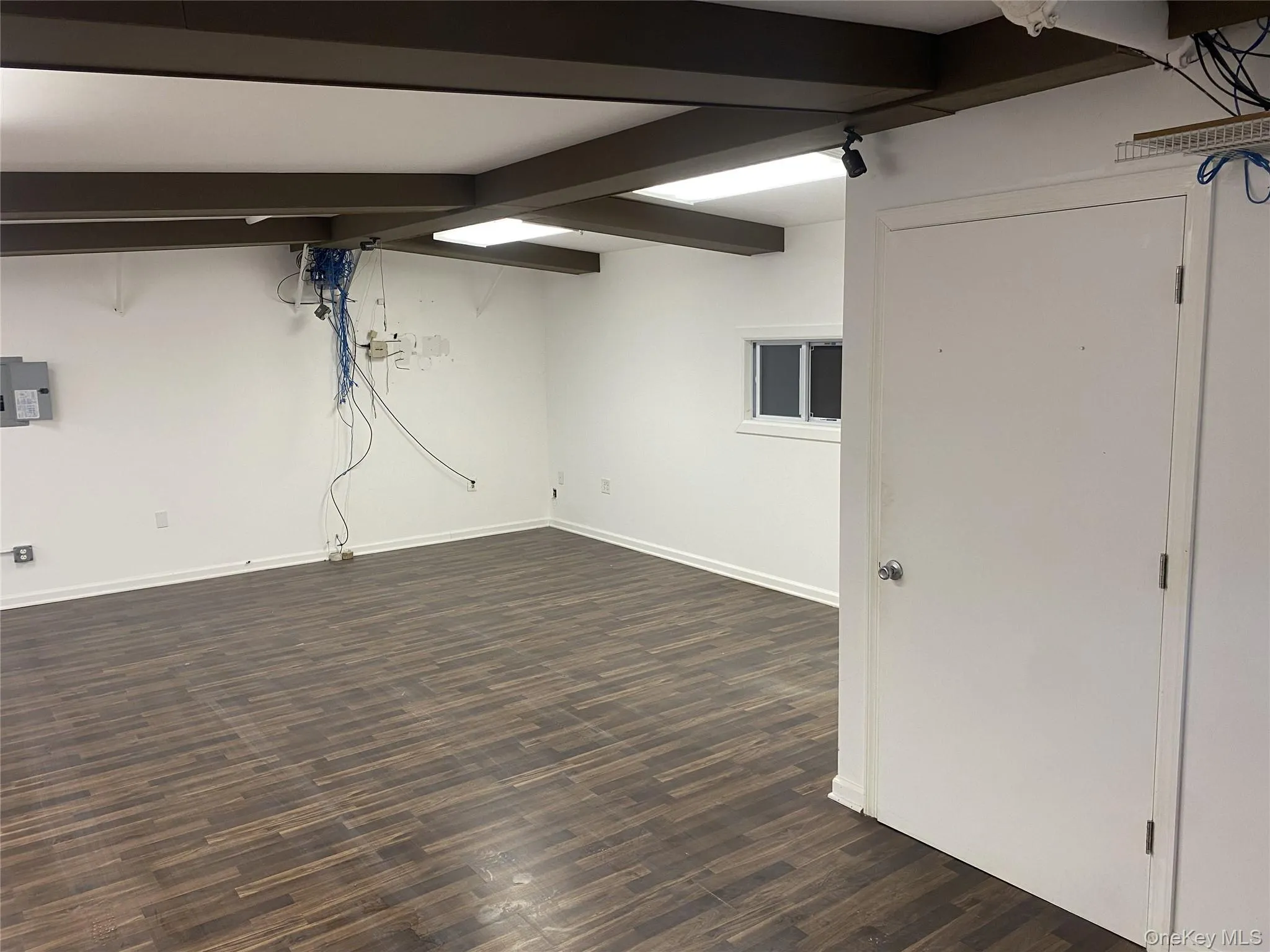 Finished basement with dark wood-type flooring and electric panel Finished basement with dark wood-type flooring and electric panel