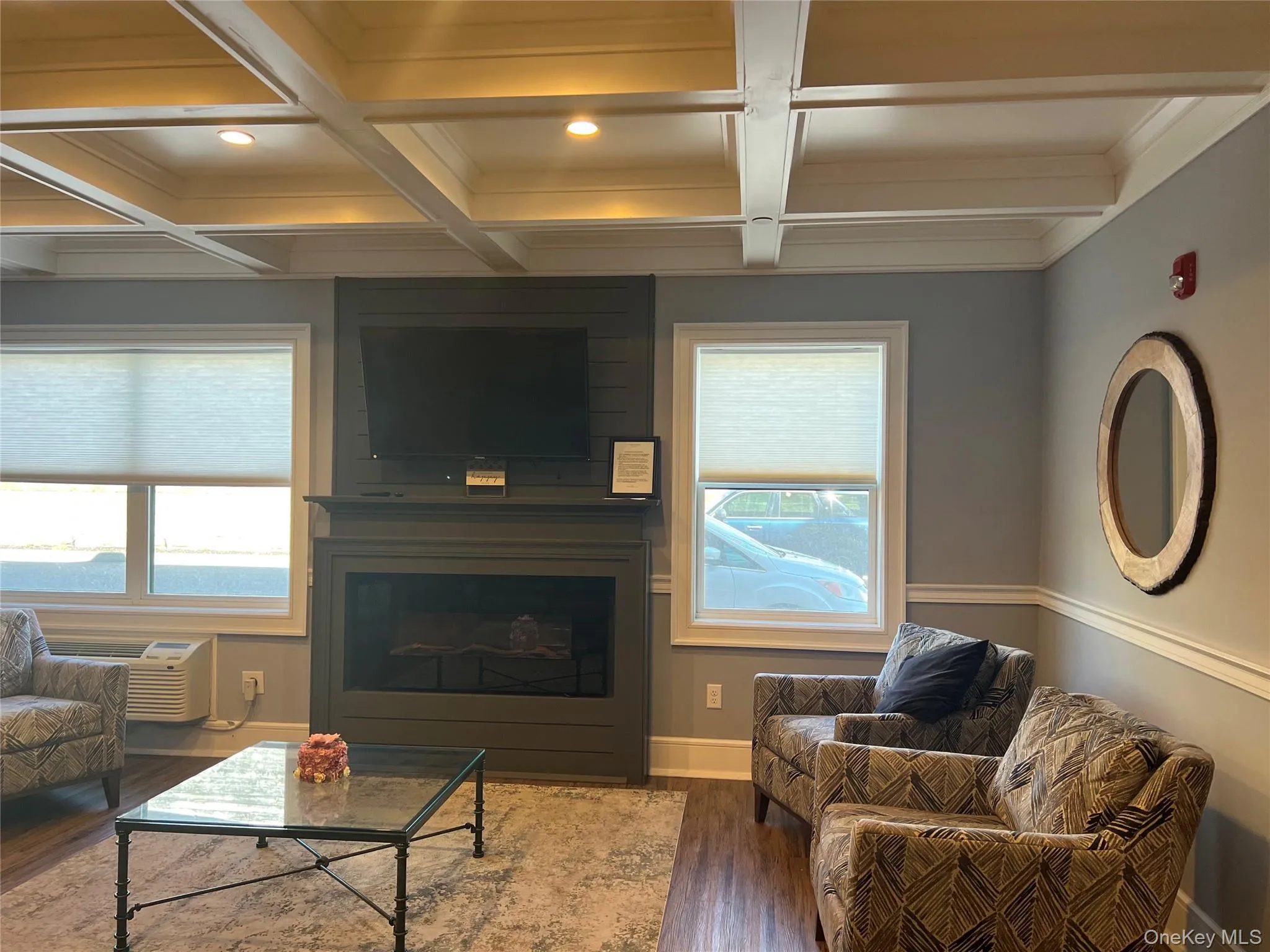 Living room with beam ceiling, coffered ceiling, a fireplace, wood finished floors, and crown molding Living room with beam ceiling, coffered ceiling, a fireplace, wood finished floors, and crown molding