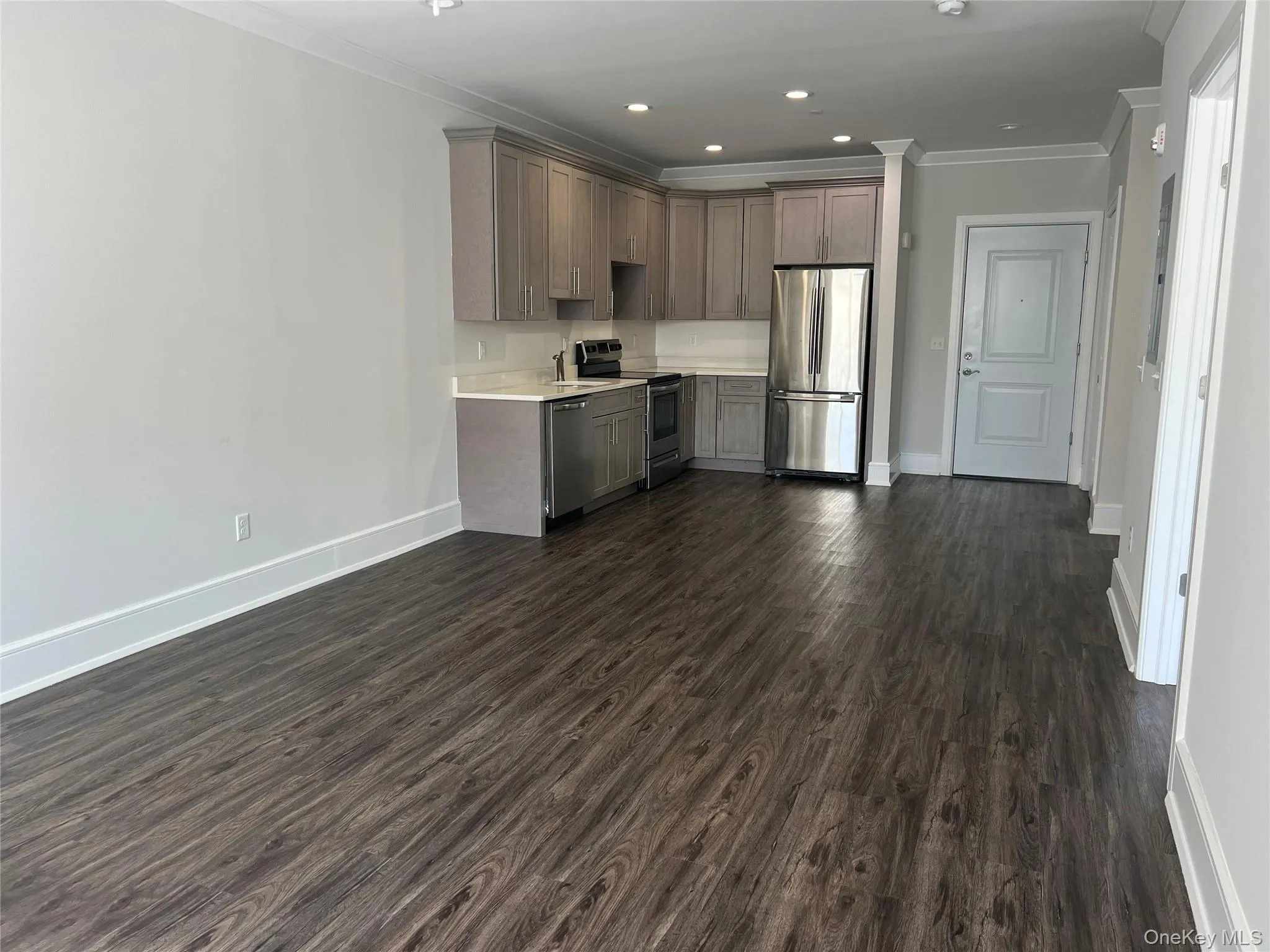 Kitchen with appliances with stainless steel finishes, light countertops, dark wood-style floors, crown molding, and recessed lighting Kitchen with appliances with stainless steel finishes, light countertops, dark wood-style floors, crown molding, and recessed lighting