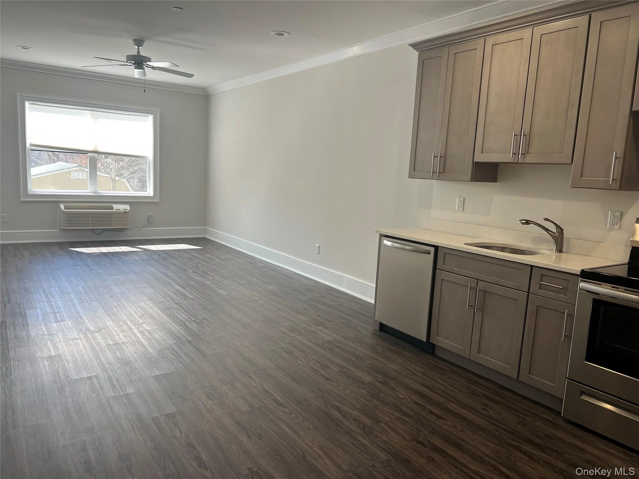 Kitchen featuring appliances with stainless steel finishes, dark wood finished floors, crown molding, light stone countertops, and ceiling fan Kitchen featuring appliances with stainless steel finishes, dark wood finished floors, crown molding, light stone countertops, and ceiling fan