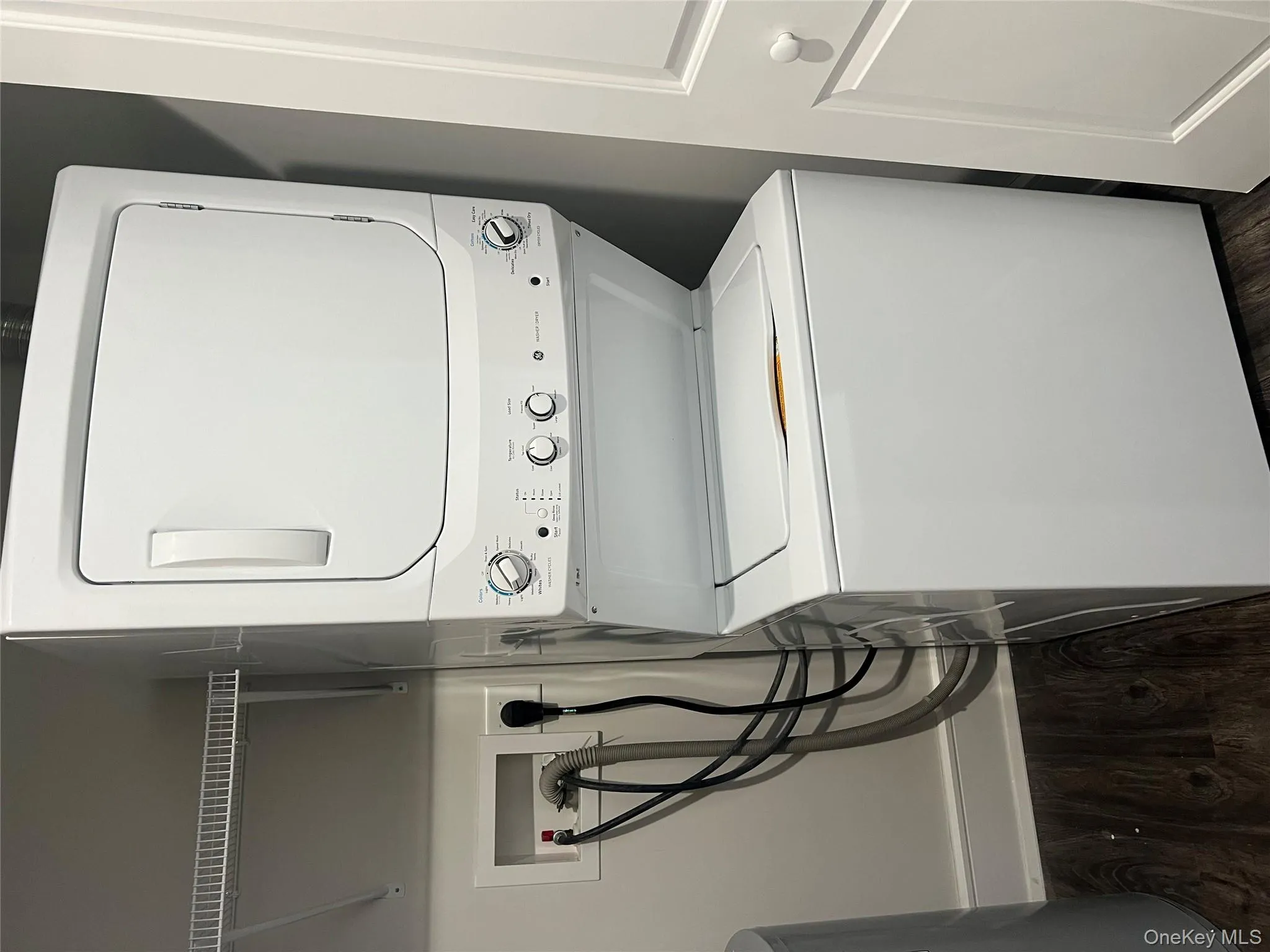 Washroom featuring dark wood finished floors and stacked washing machine and dryer Washroom featuring dark wood finished floors and stacked washing machine and dryer