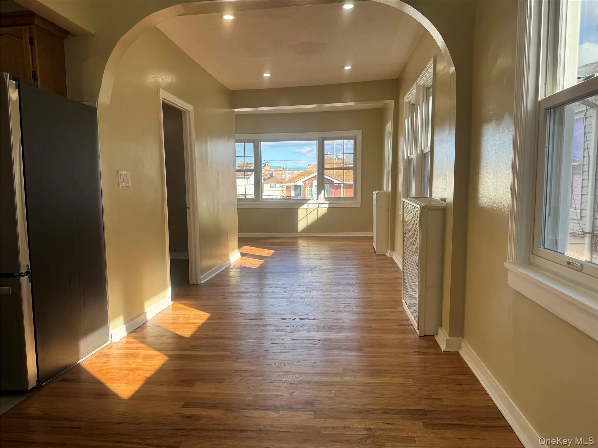 Corridor with arched walkways, light wood-style floors, and recessed lighting Corridor with arched walkways, light wood-style floors, and recessed lighting